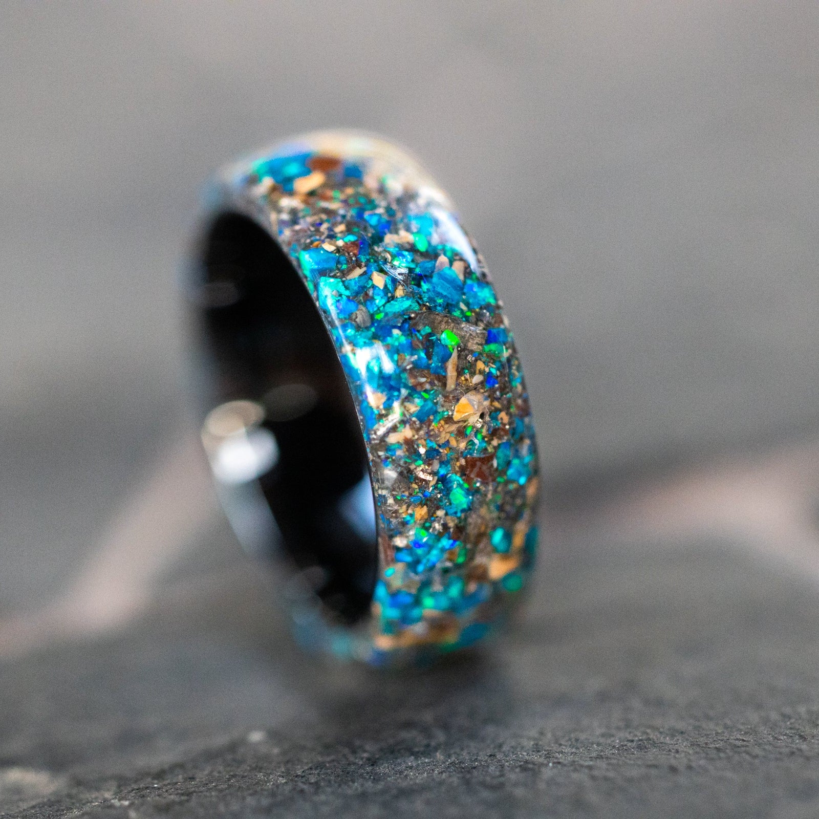 Close up of genuine Mosasaur bone, Dinosaur Gembone, and Campo del Cielo meteorite shavings suspended in blue opal inlay on endless ceramic ring