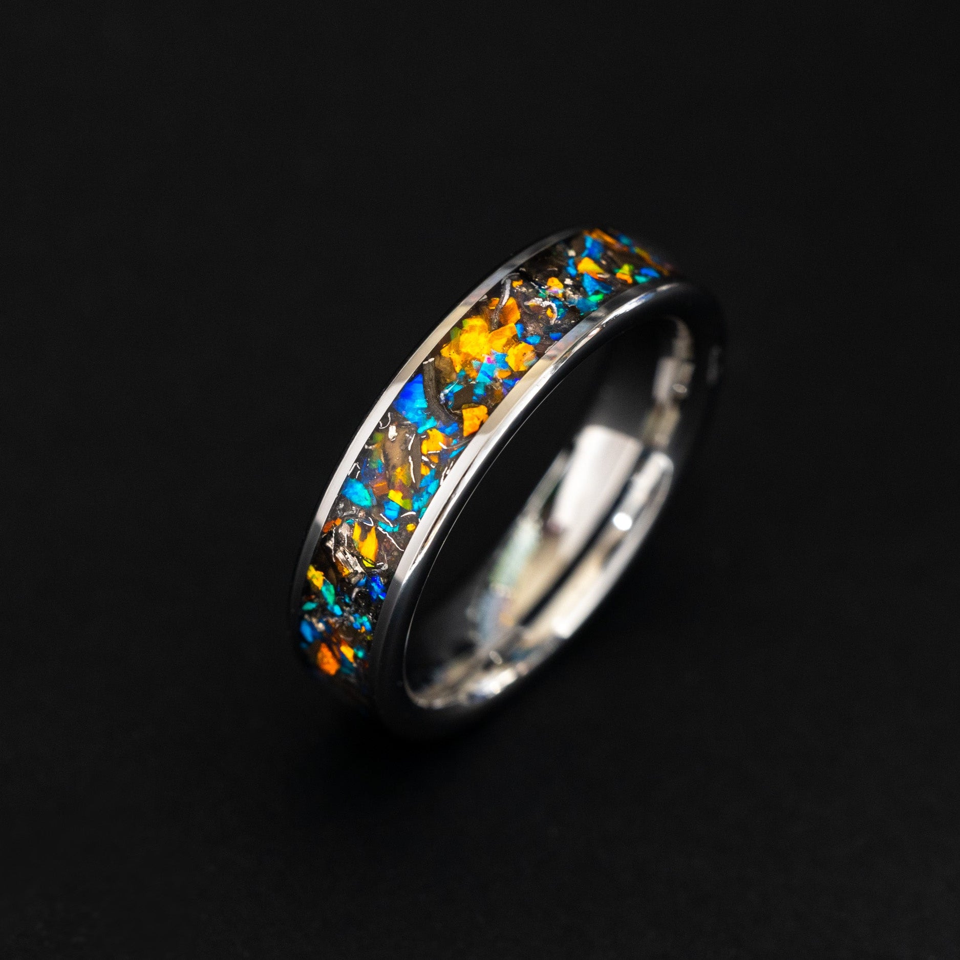 Close up of meteorite shavings and contrasting blue and orange opals in a 6mm tungsten ring