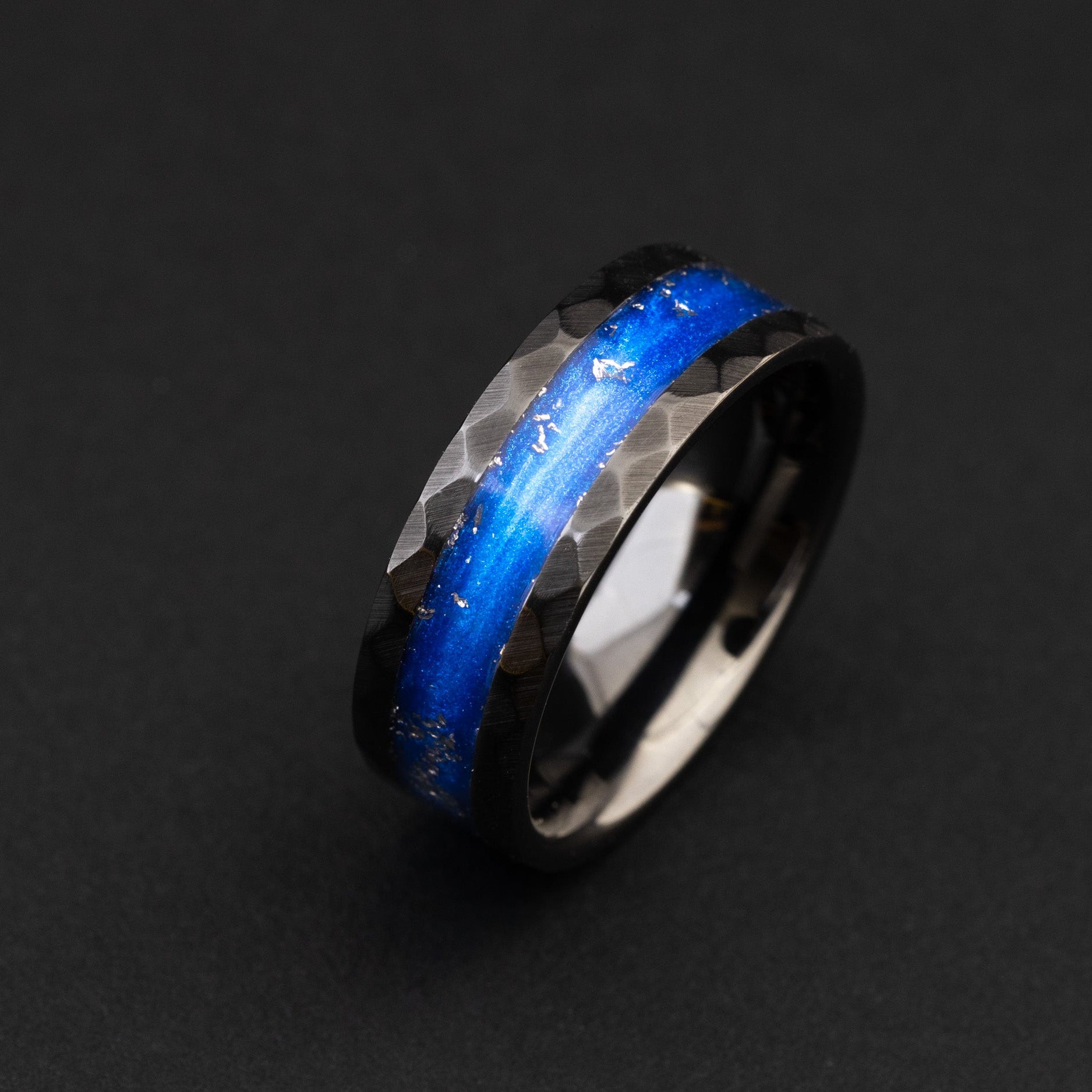 hammered black ceramic wedding band featuring celestial meteorite fragments and blue inlay.