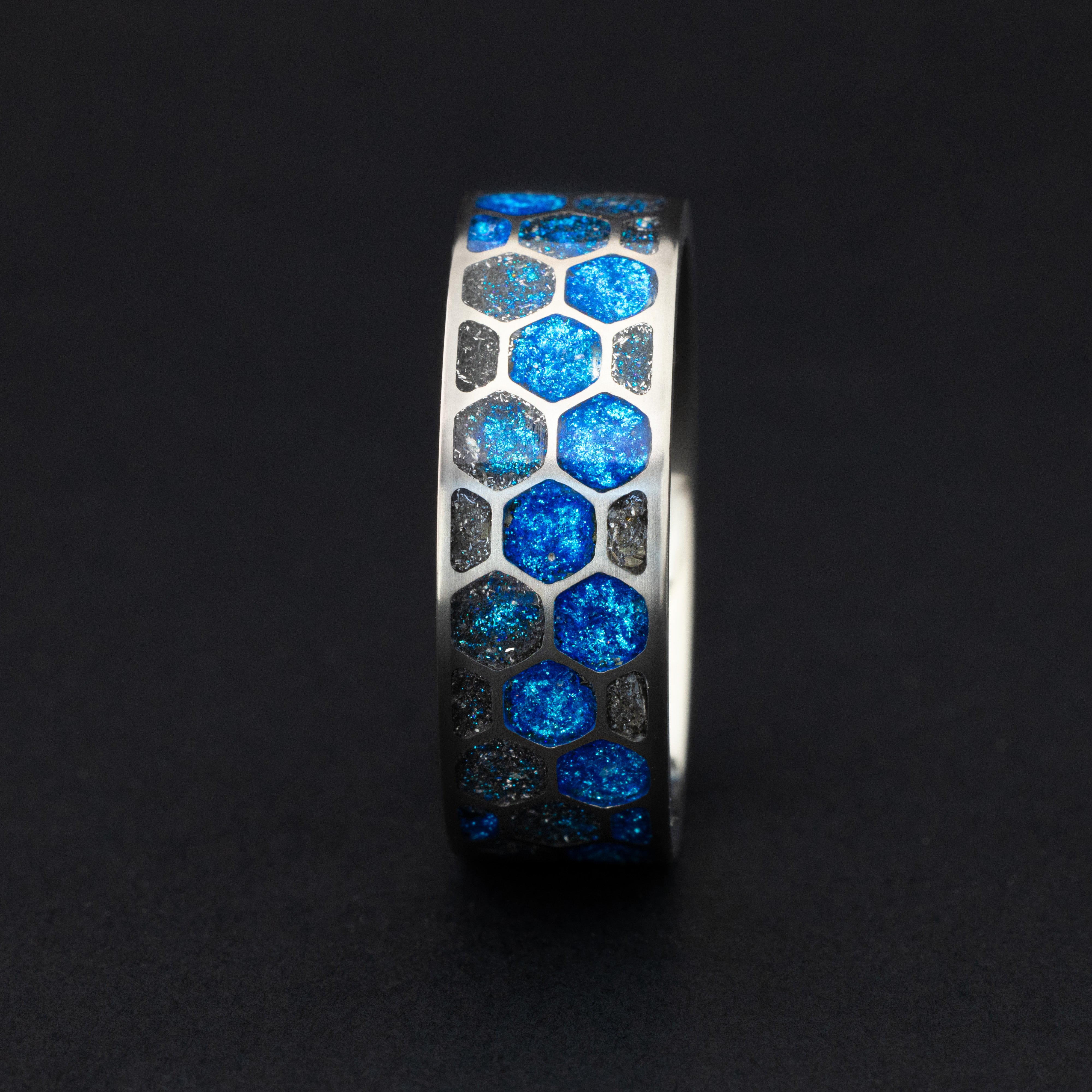 Blue Hex Glow ring glowing blue in total darkness showing Campo del Cielo meteorite pieces illuminated in electric blue glow within honeycomb cells