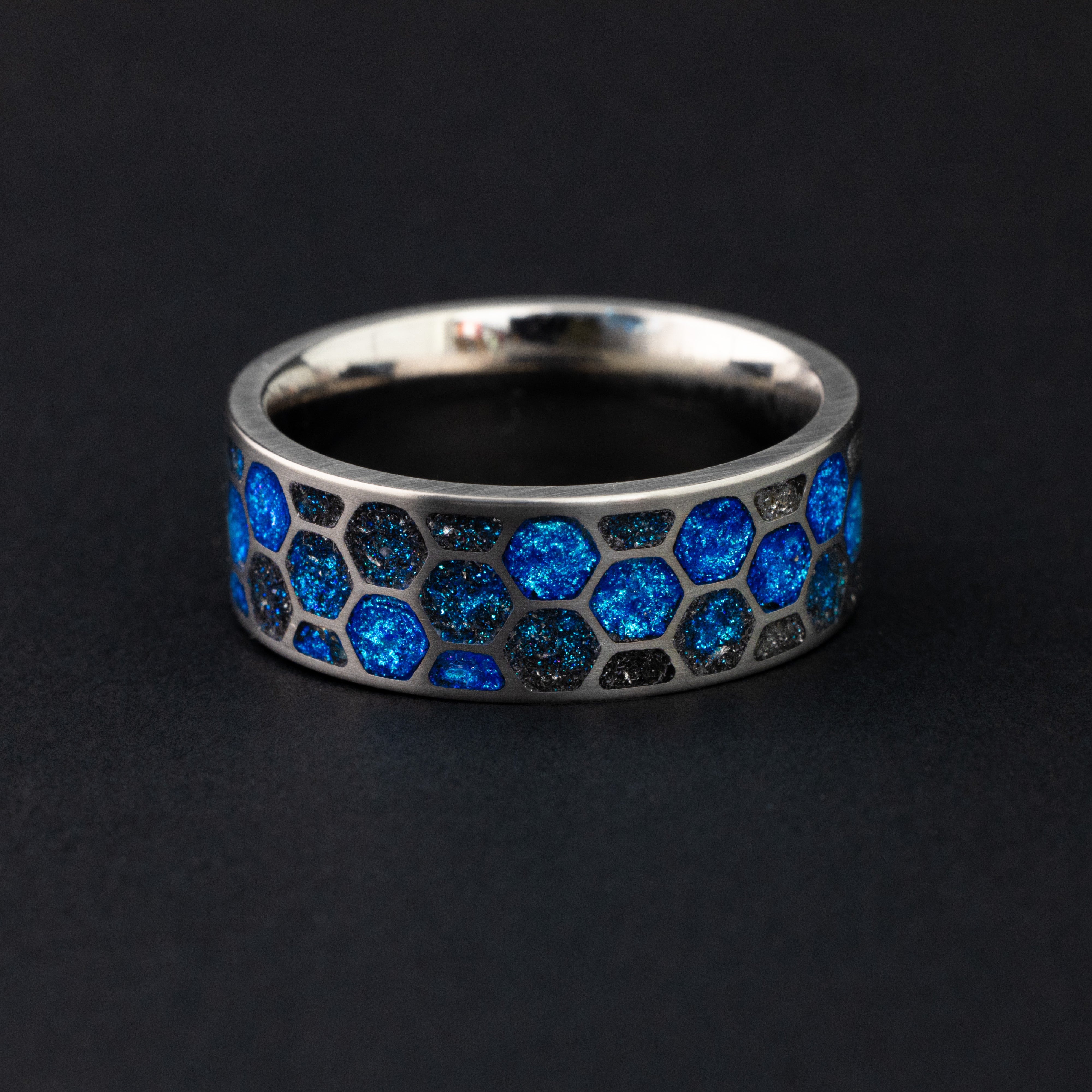 Blue Hex Glow ring glowing blue in total darkness showing Campo del Cielo meteorite pieces illuminated in electric blue glow within honeycomb