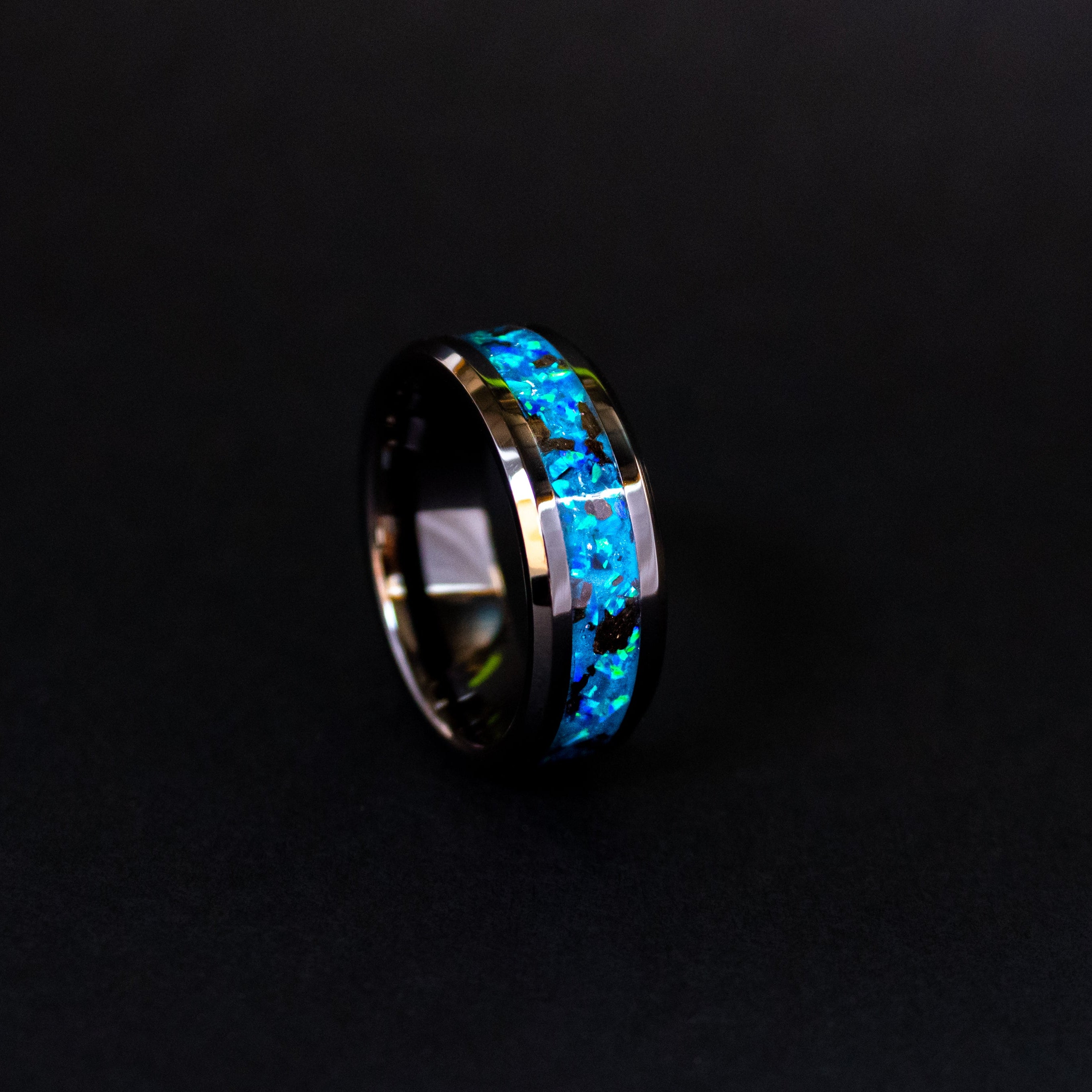 Blue Megalodon Glow ring glowing blue in total darkness showing Megalodon tooth fragments suspended in electric blue glow in the dark inlay