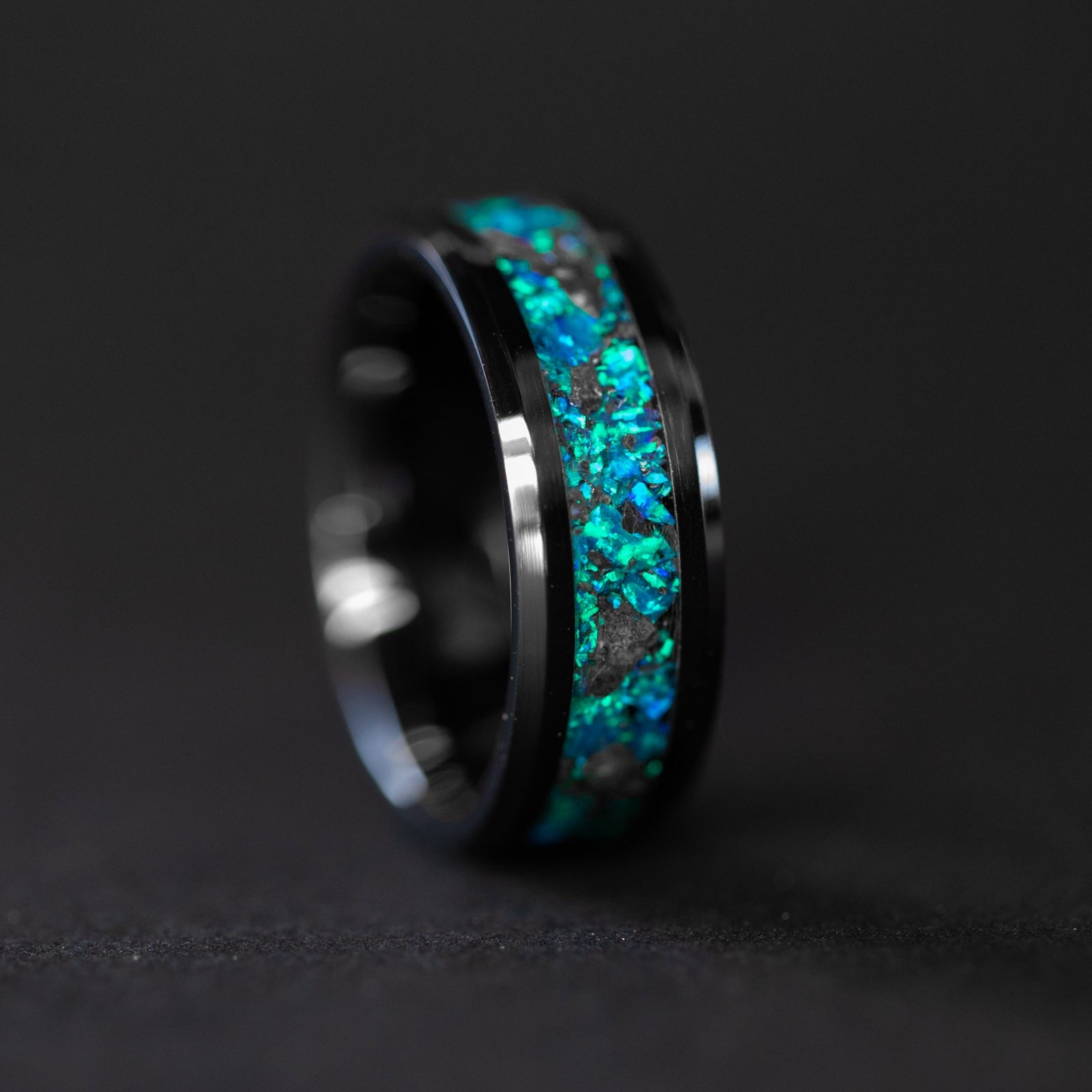 Detail shot of the Blue Moon ring showing authentic lunar meteorite fragments catching light through deep blue opal inlay on black ceramic band