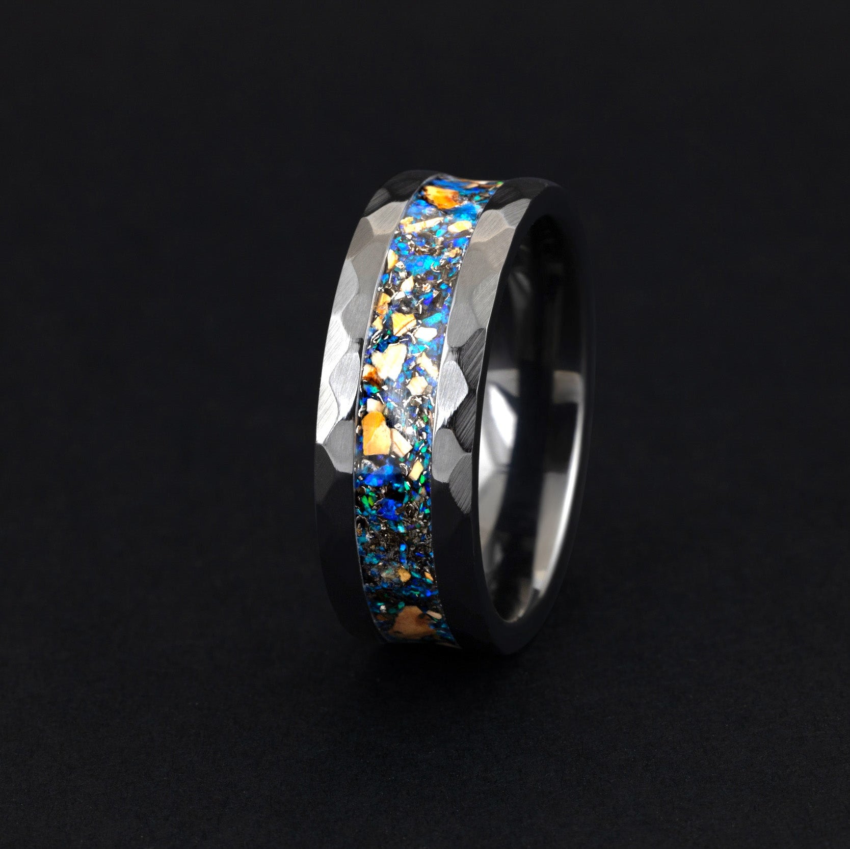 Close up of genuine Velociraptor fossil shards and meteorite in a hammered black wedding band.