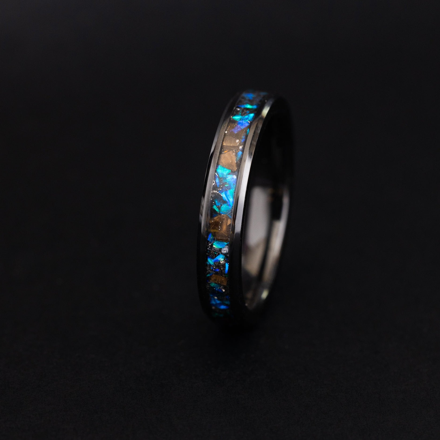 Close up of T-Rex bone and blue opals in a sleek 4mm ceramic ring.