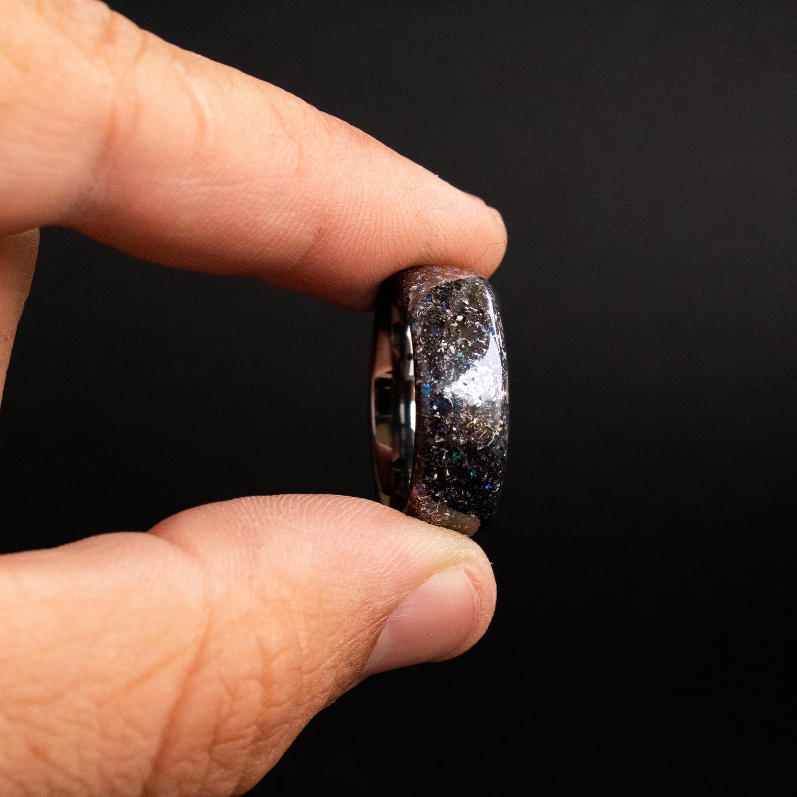 Detail shot of the Blue Spark ring showing authentic Campo del Cielo meteorite shavings and subtle blue opal accents catching light on endless tungsten band