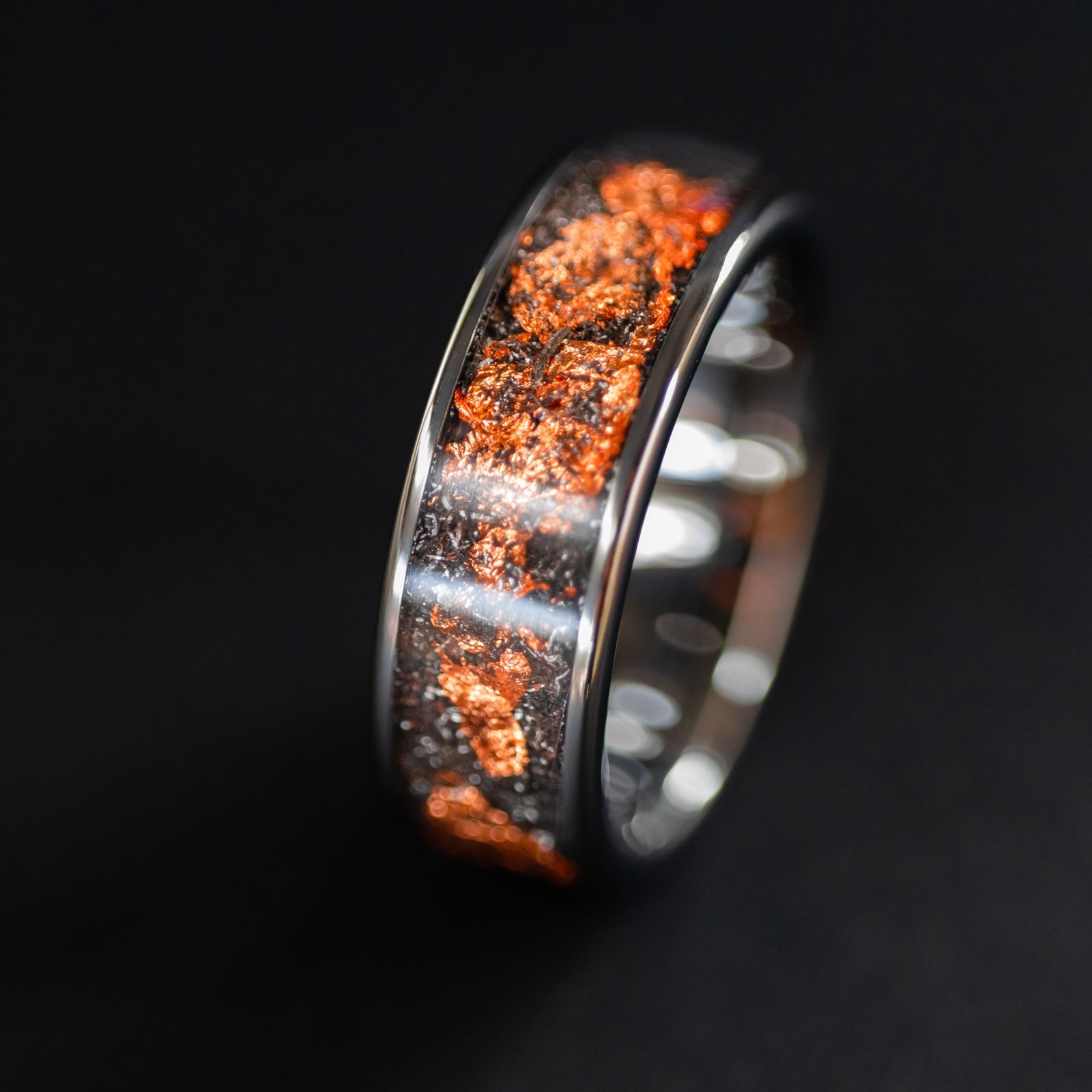 Close up of genuine Campo del Cielo meteorite shavings mixed with real copper flake inlay on wide channel tungsten ring
