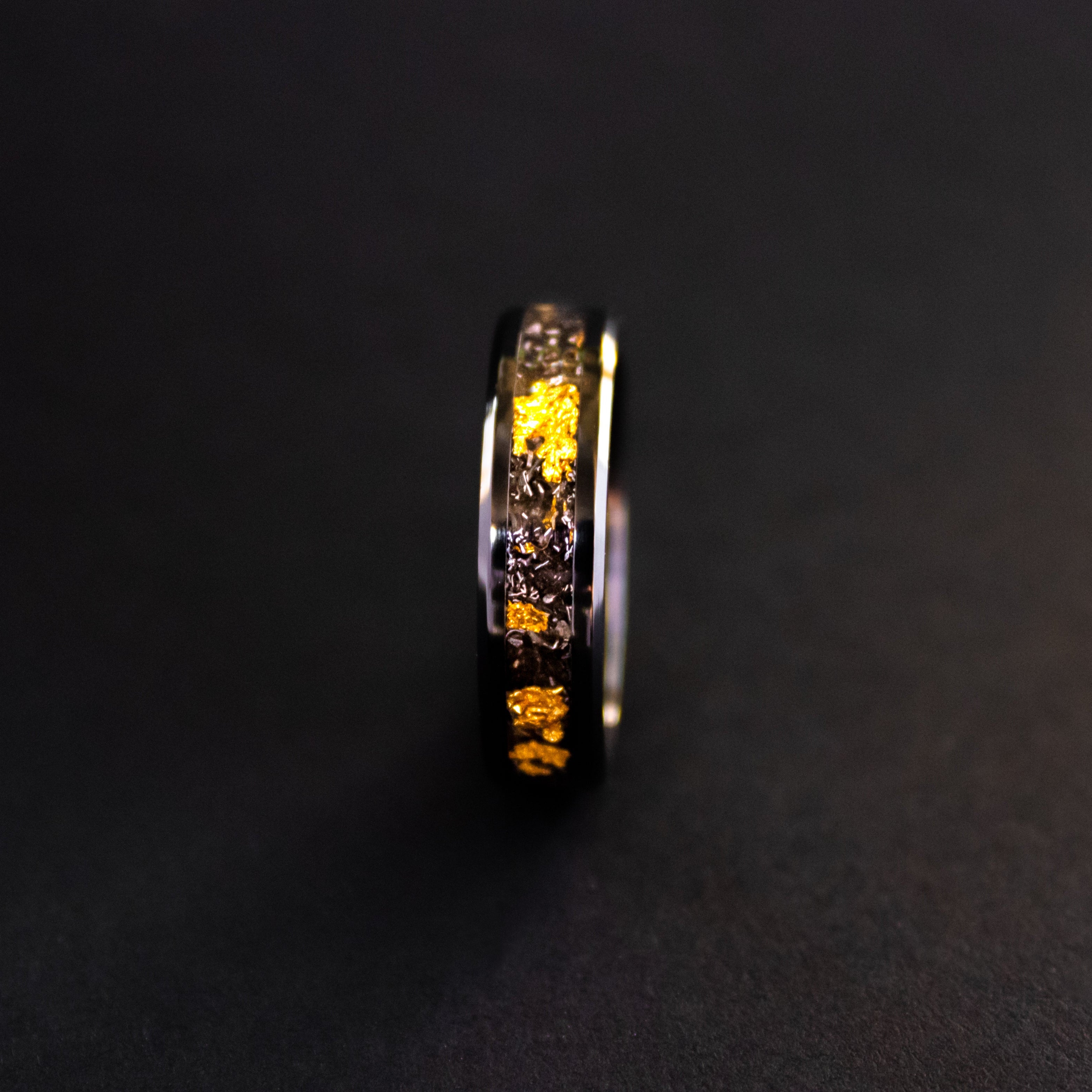 Close up of genuine Campo del Cielo meteorite shavings mixed with real gold metal flake inlay on beveled black ceramic ring