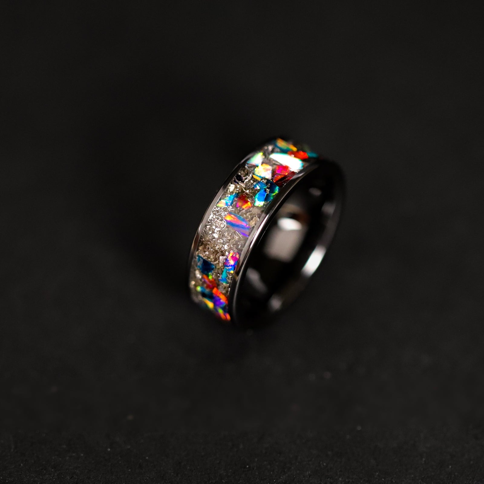 Close up of genuine Campo del Cielo meteorite shavings surrounded by large multi-color opal pieces in blue red purple yellow green white and rainbow on ceramic ring