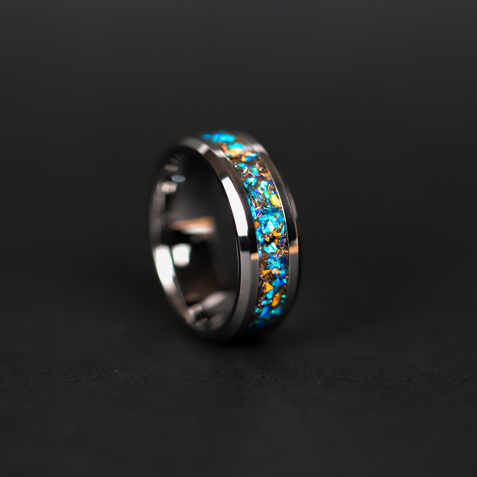 Detail shot of the Cobalt Velociraptor ring showing authentic Velociraptor bone fragments and meteorite shavings catching light through blue opal inlay on tungsten band