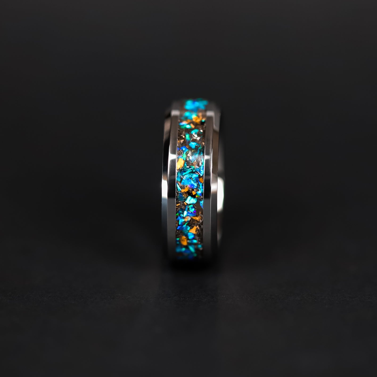 Shot of the Cobalt Velociraptor ring showing authentic Velociraptor bone fragments and meteorite shavings catching light through blue opal inlay on tungsten band