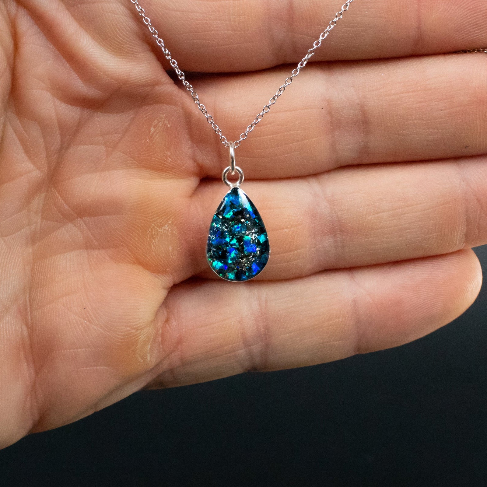 Close-up of the Comet Blue Drop blue opal necklace showing Campo Del Cielo iron meteorite fragments set with vivid blue opal