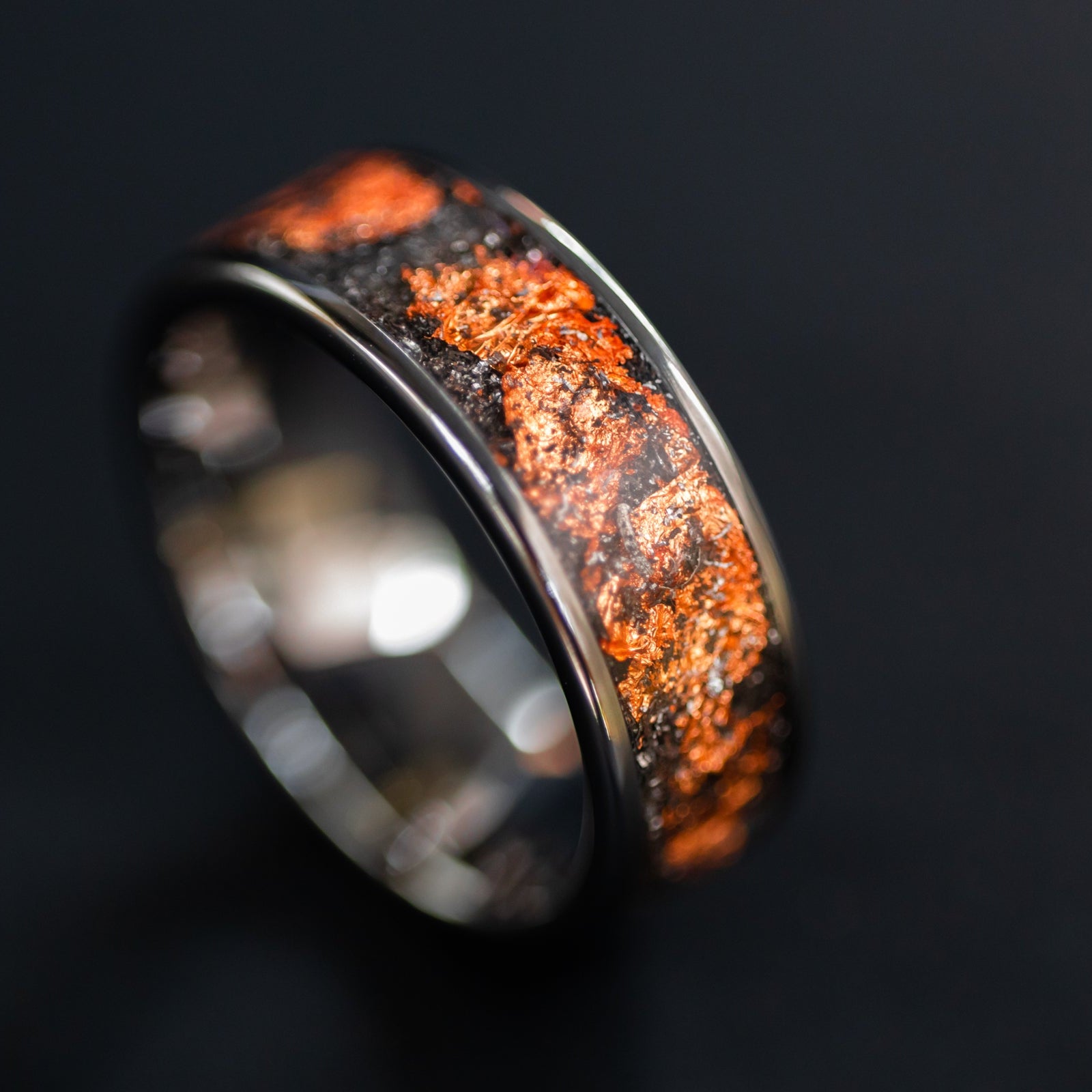 Detail shot of the Copper Meteorite ring showing authentic Campo del Cielo meteorite shavings and warm copper flake catching light on wide channel tungsten band