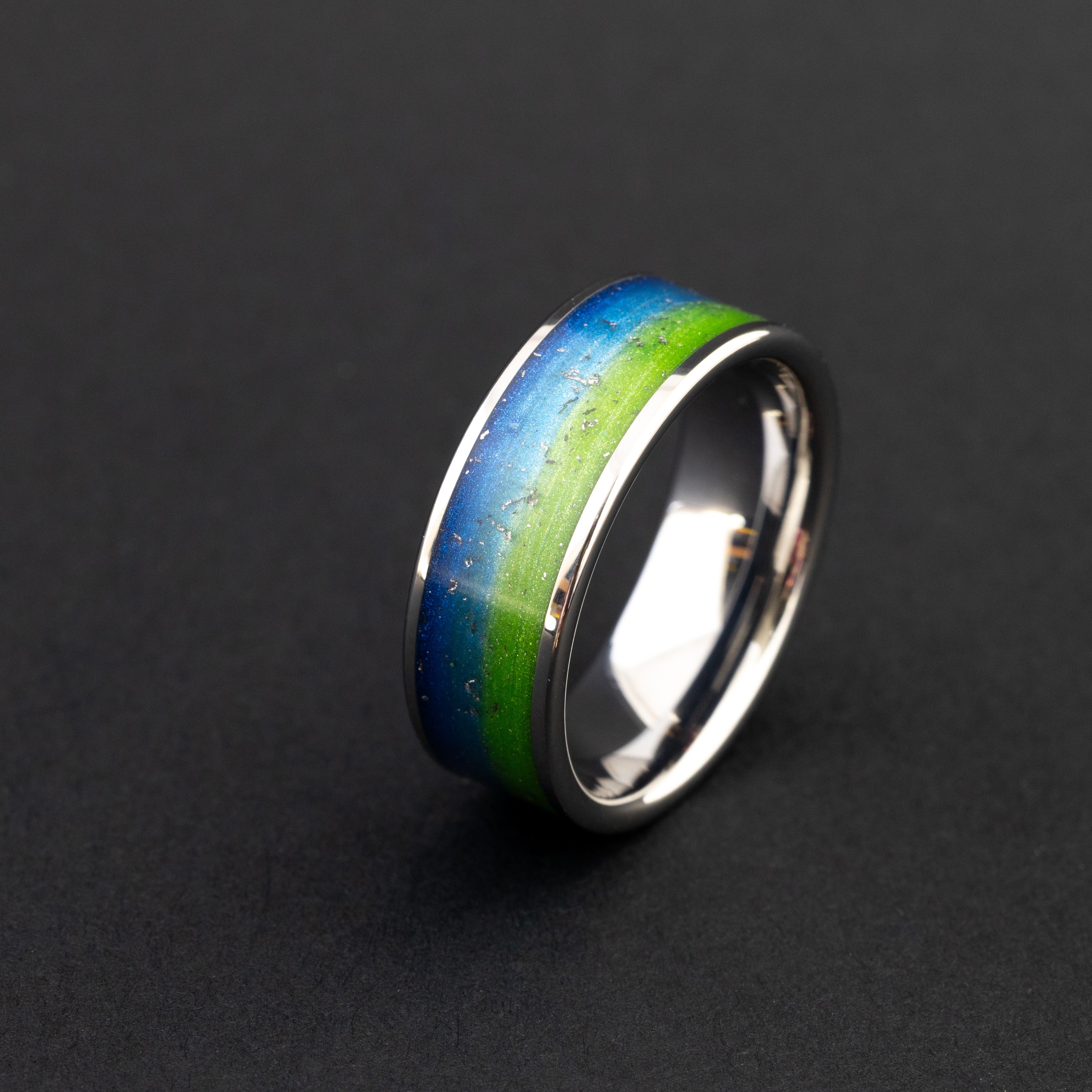 Close up of Gibeon meteorite shavings in a vibrant blue and green 8mm tungsten ring.