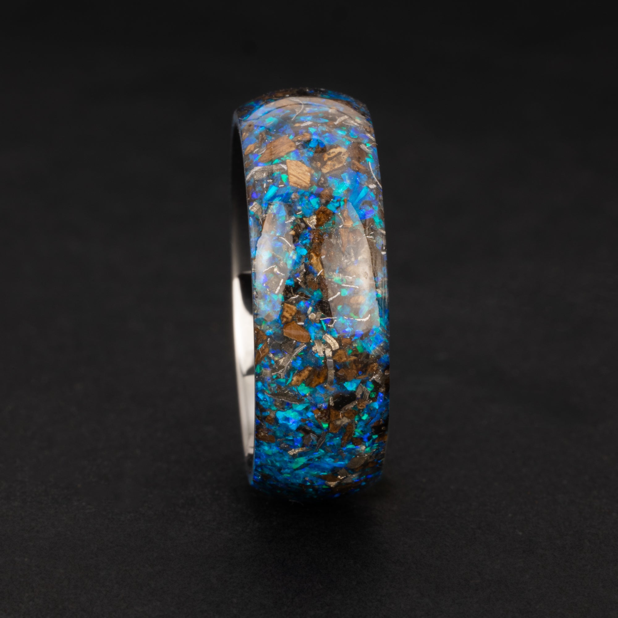 Close-up of the Endless Blue Rex ring showing Campo Del Cielo iron meteorite, real T-Rex bone, and bright blue opal in an endless tungsten band