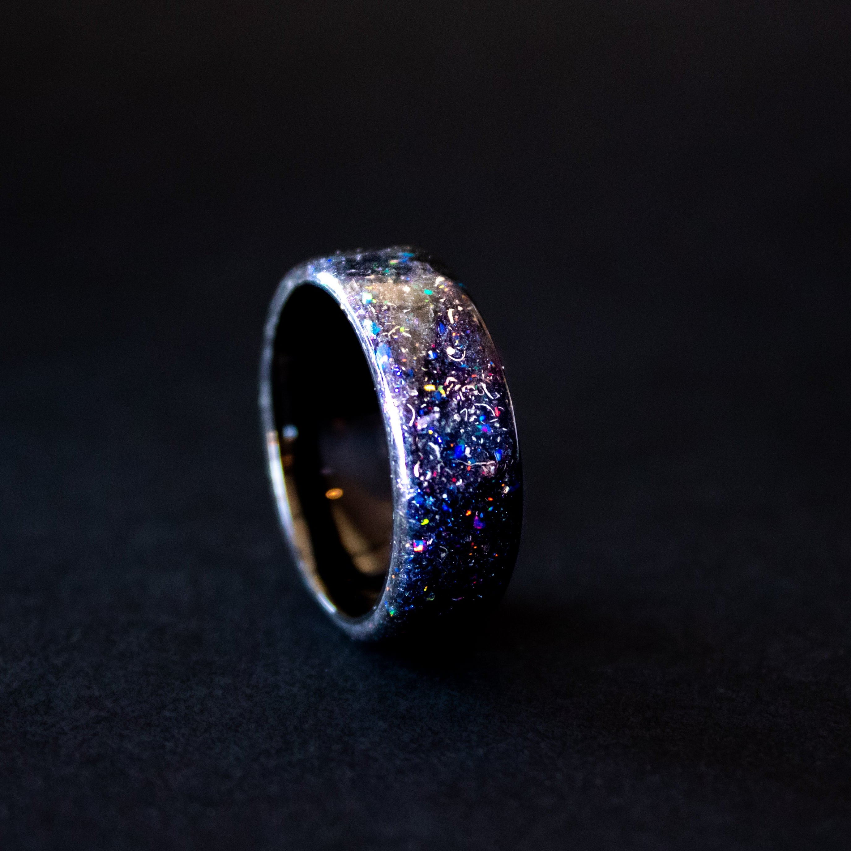 Detail shot of the Endless Galaxy ring showing authentic Campo del Cielo meteorite shavings catching light through blue and purple opal galaxy pigment inlay on endless ceramic band