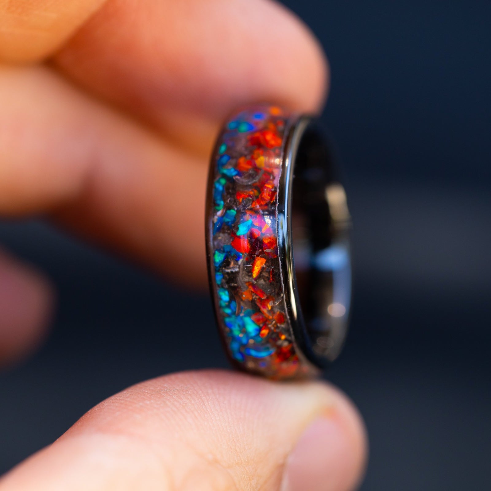 Detail shot of the Fire and Ice Wide ring showing authentic Campo del Cielo meteorite shavings bridging the transition between red and blue opal halves on ceramic band