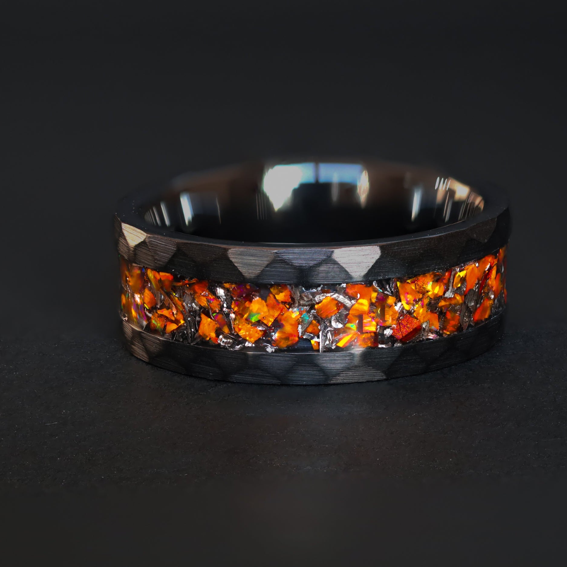 Handcrafted hammered black ceramic wedding band featuring celestial meteorite fragments and magma orange glow.