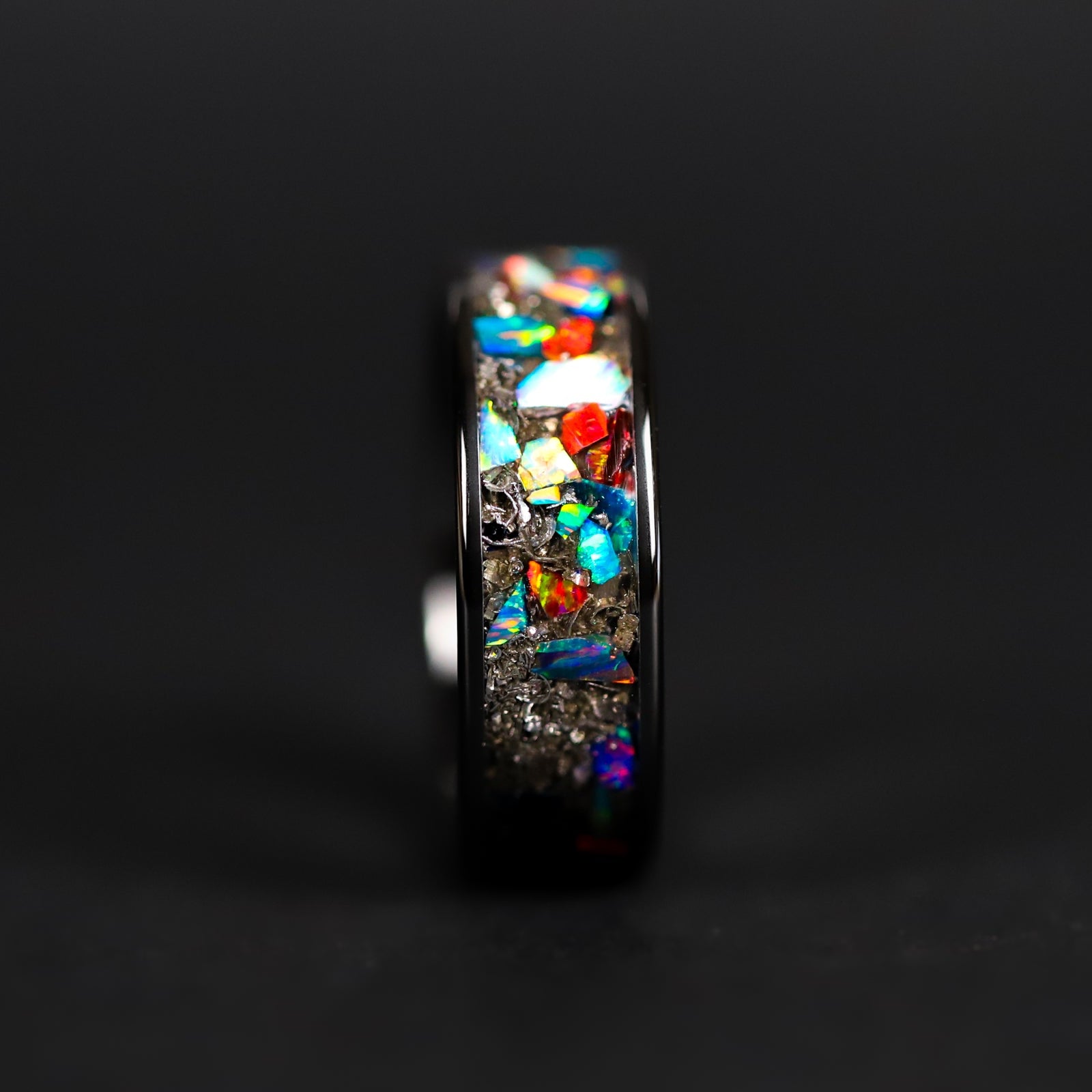 Detail shot of the Full Spectrum ring showing authentic Campo del Cielo meteorite shavings and large pieces of multi-color opal catching light on wide channel ceramic band