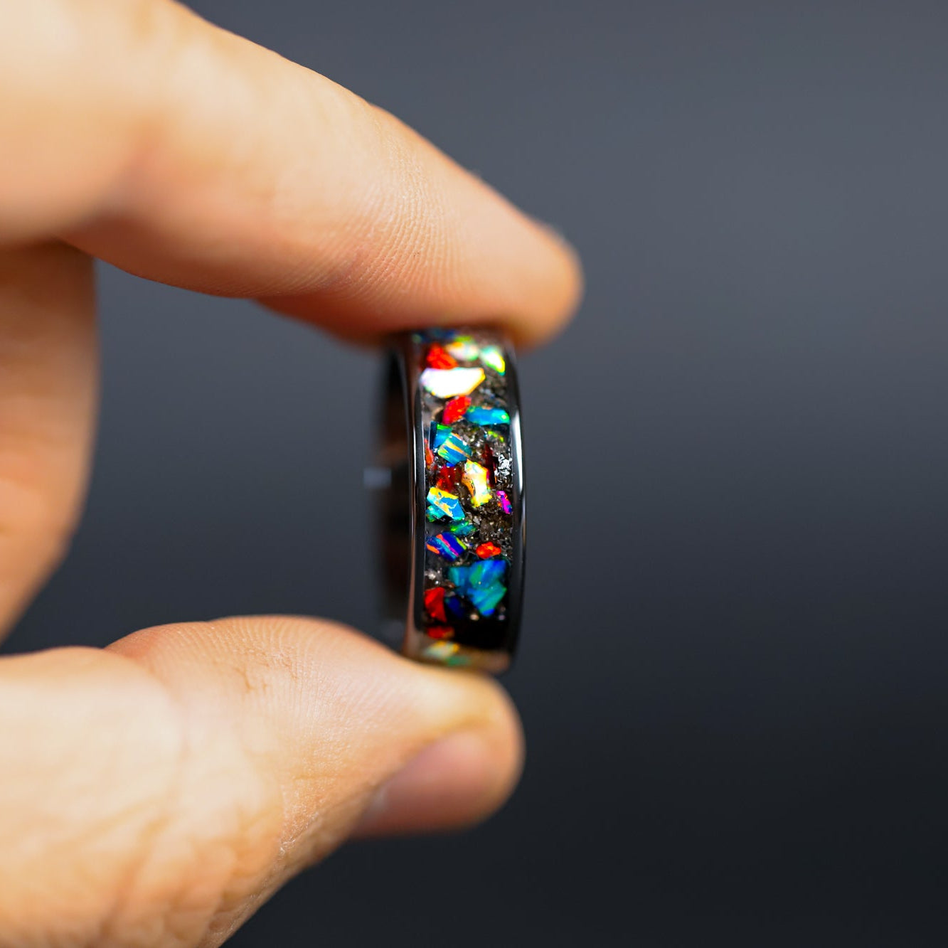 Detail shot of the Full Spectrum ring showing authentic Campo del Cielo meteorite shavings and large pieces of multi-color opal catching light on wide channel ceramic