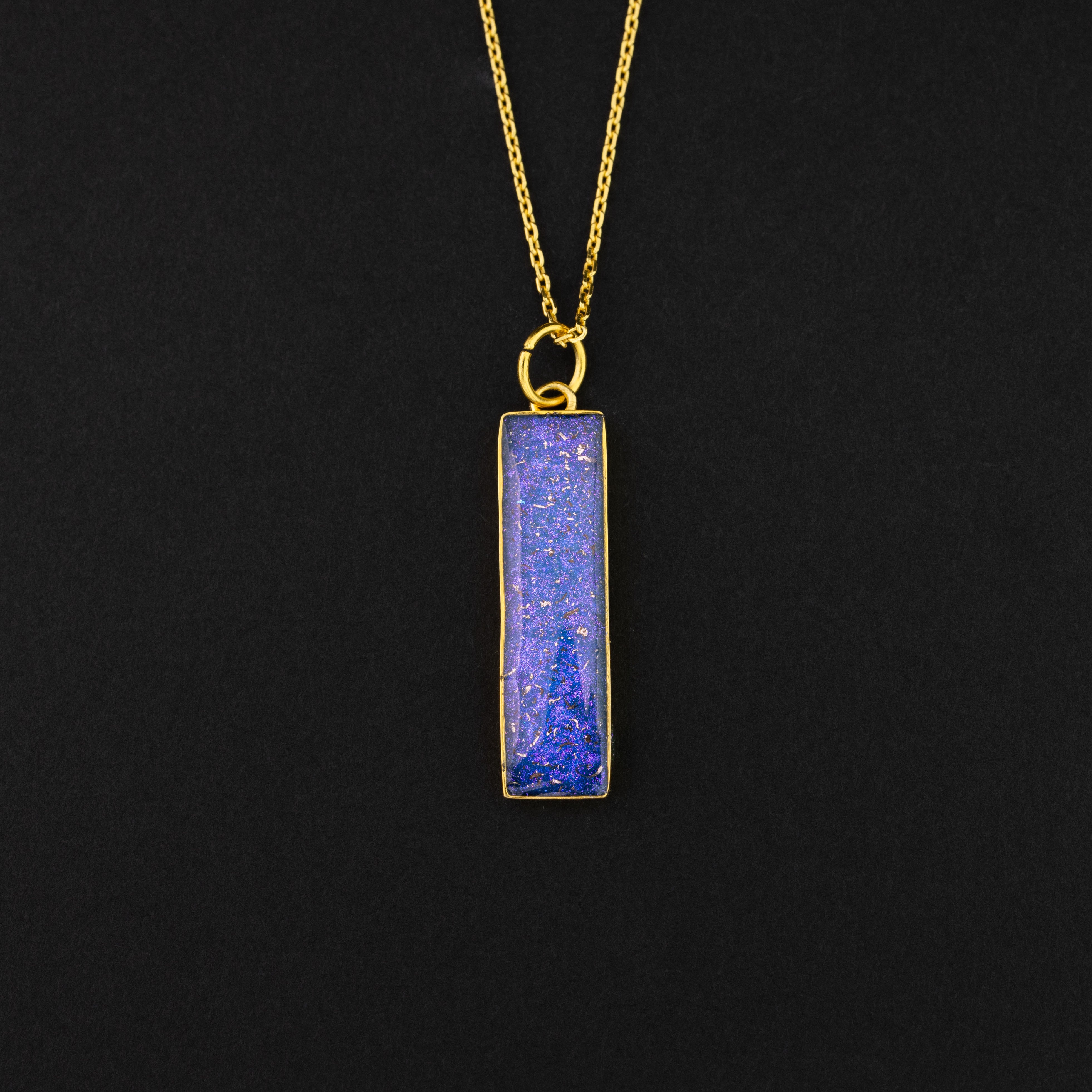 Close-up of the Galaxy Bar Gold pendant showing authentic Campo Del Cielo meteorite fragments set with blue and purple opals and glitter