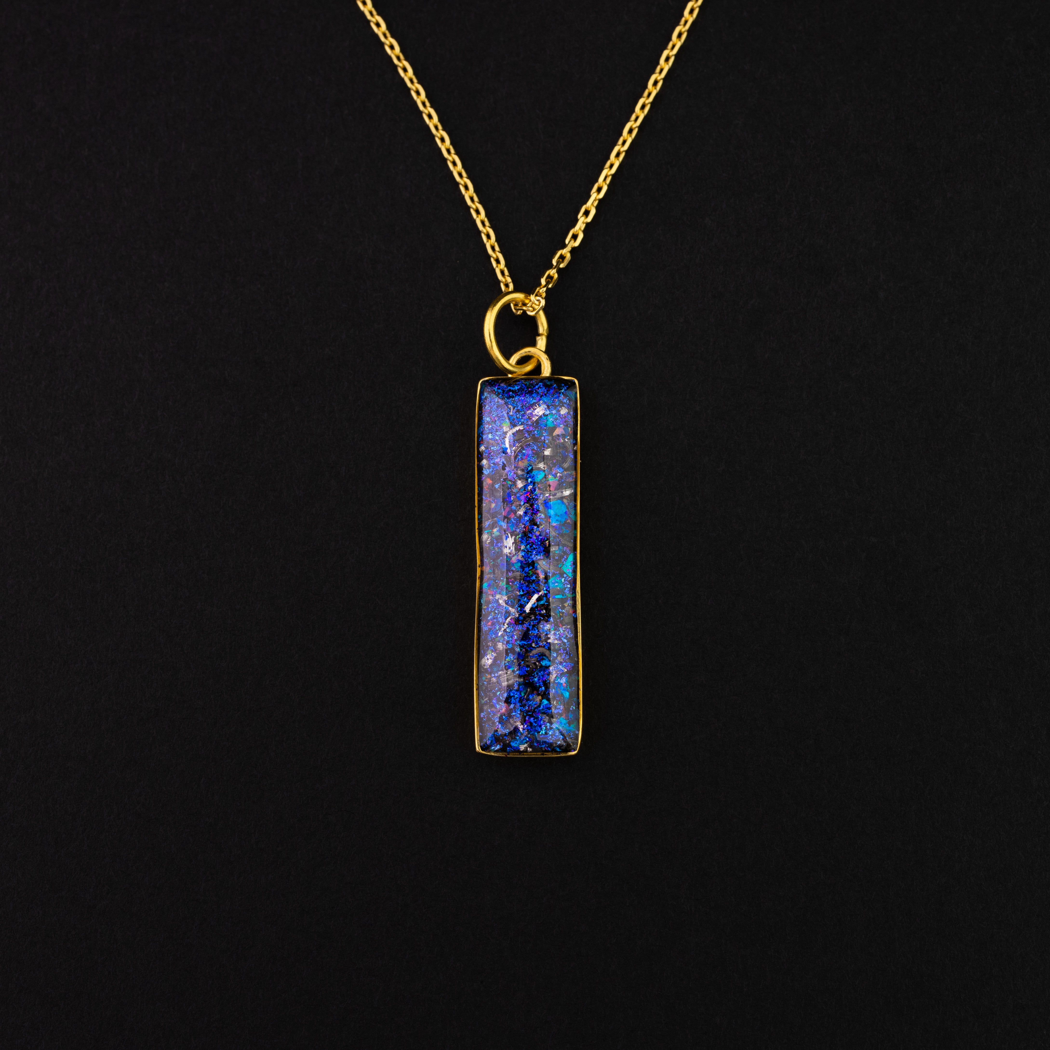 Close-up of the Galaxy Bar Gold pendant showing authentic Campo Del Cielo meteorite fragments set with blue and purple opals and pigment