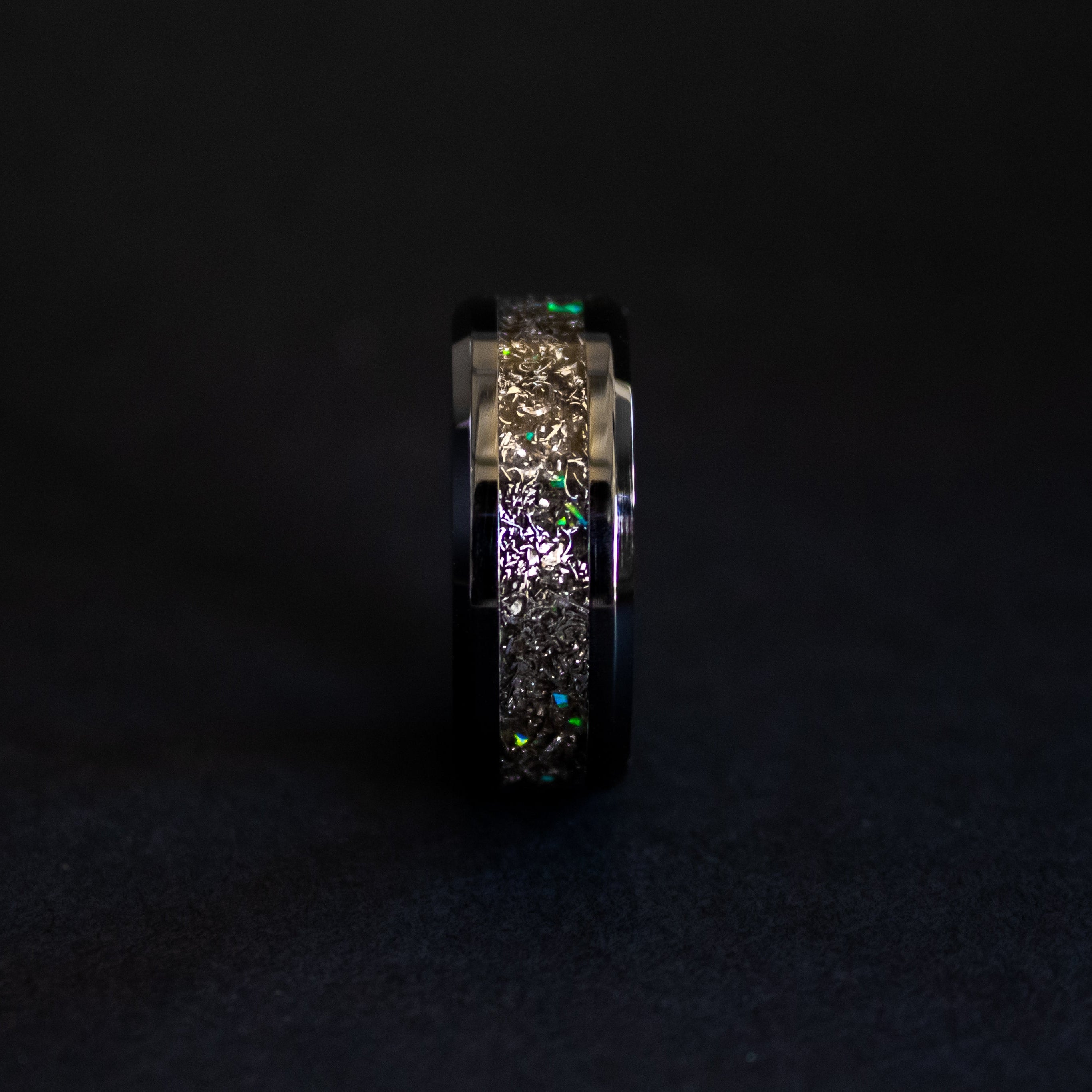 Close up of genuine Gibeon meteorite shavings with scattered green opal accents on beveled black ceramic ring