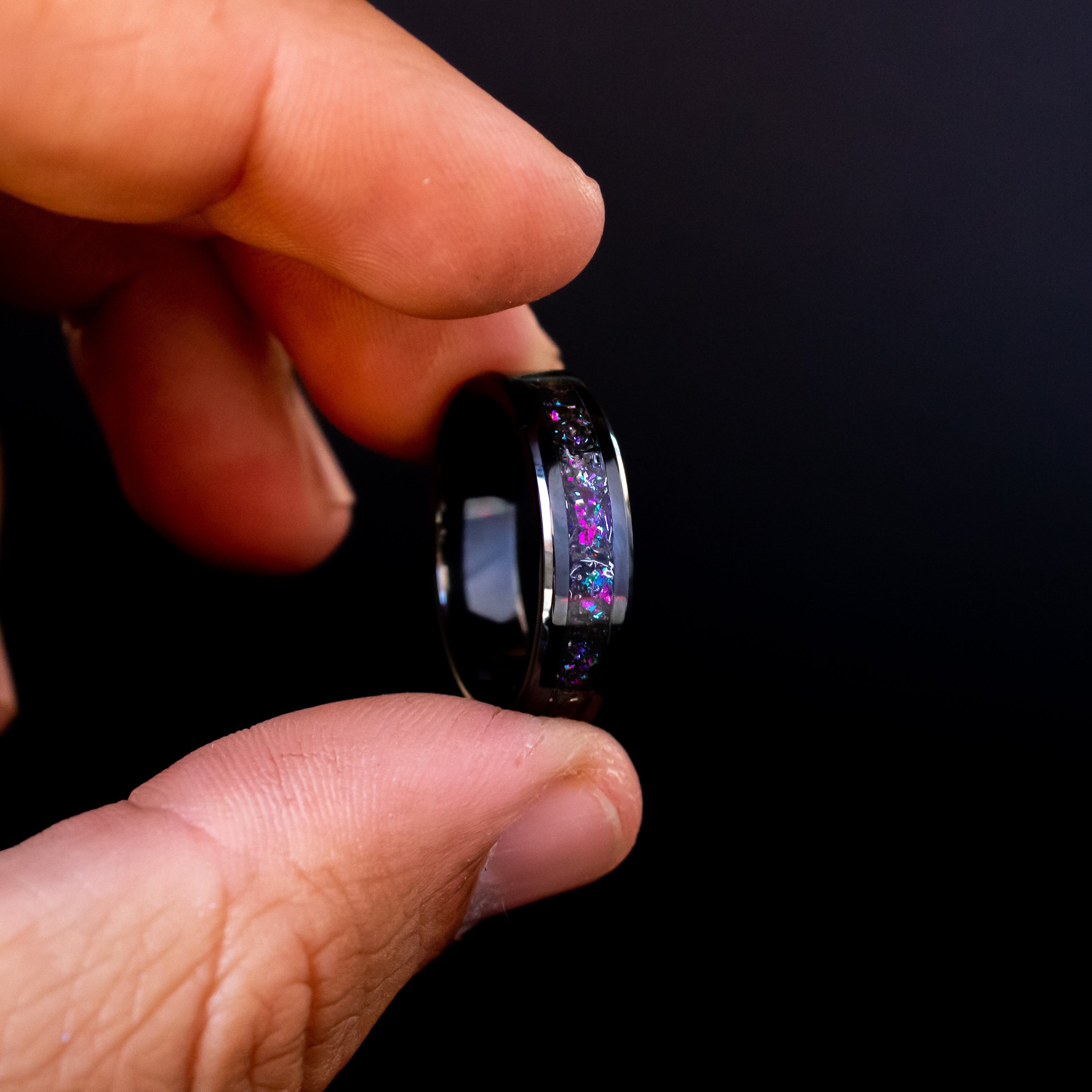 Close up of genuine Gibeon meteorite shavings suspended in pink and purple galaxy glitter inlay on beveled black ceramic ring