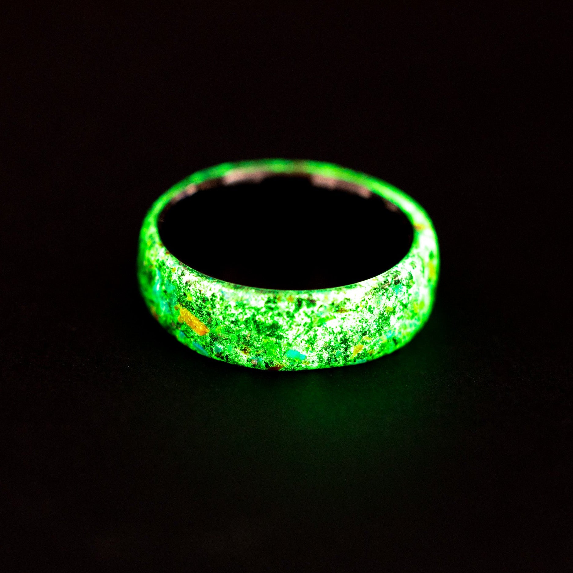 Close up of dinosaur bone and green opals in a glowing endless ceramic ring.