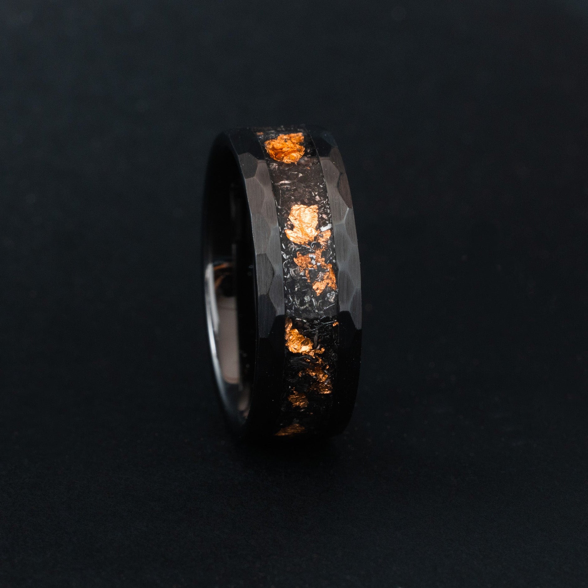 Close up of Campo del Cielo meteorite shavings and copper flakes in a hammered black ceramic ring.