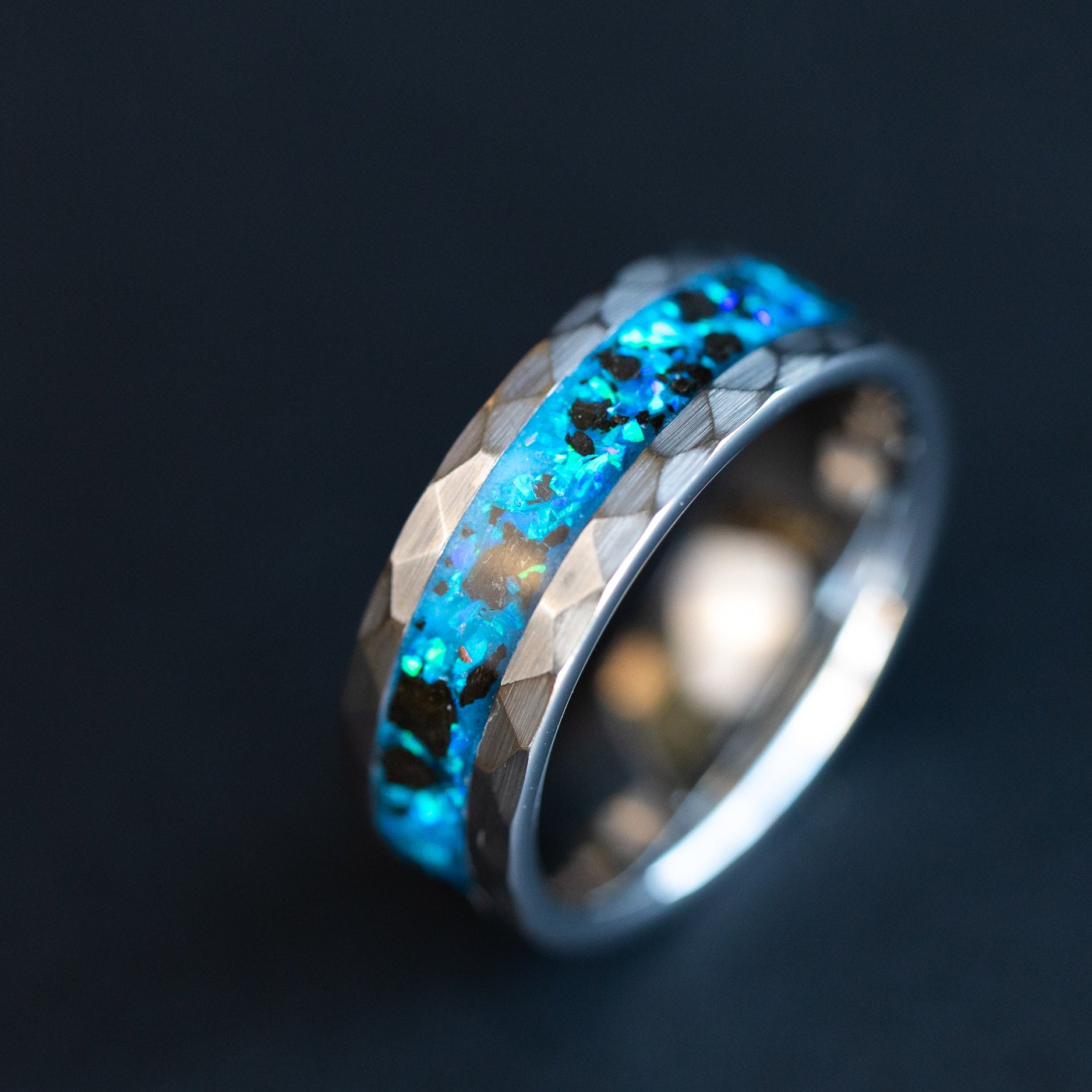 Hammered Leviathan ring glowing blue in total darkness showing Megalodon tooth fossil suspended in electric blue glow in the dark inlay