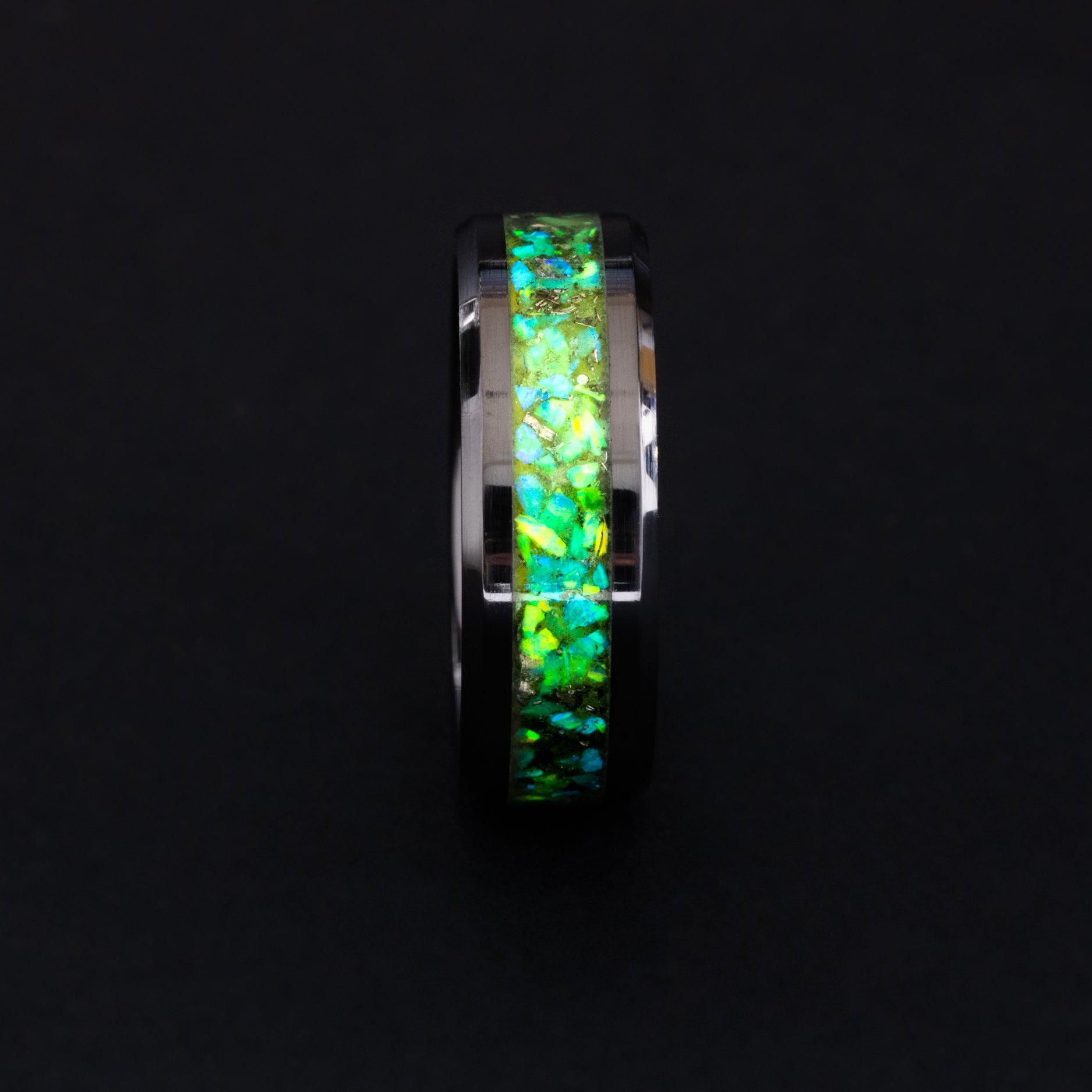 Close up of meteorite shavings and lime green opals in a glowing 8mm beveled ceramic ring.