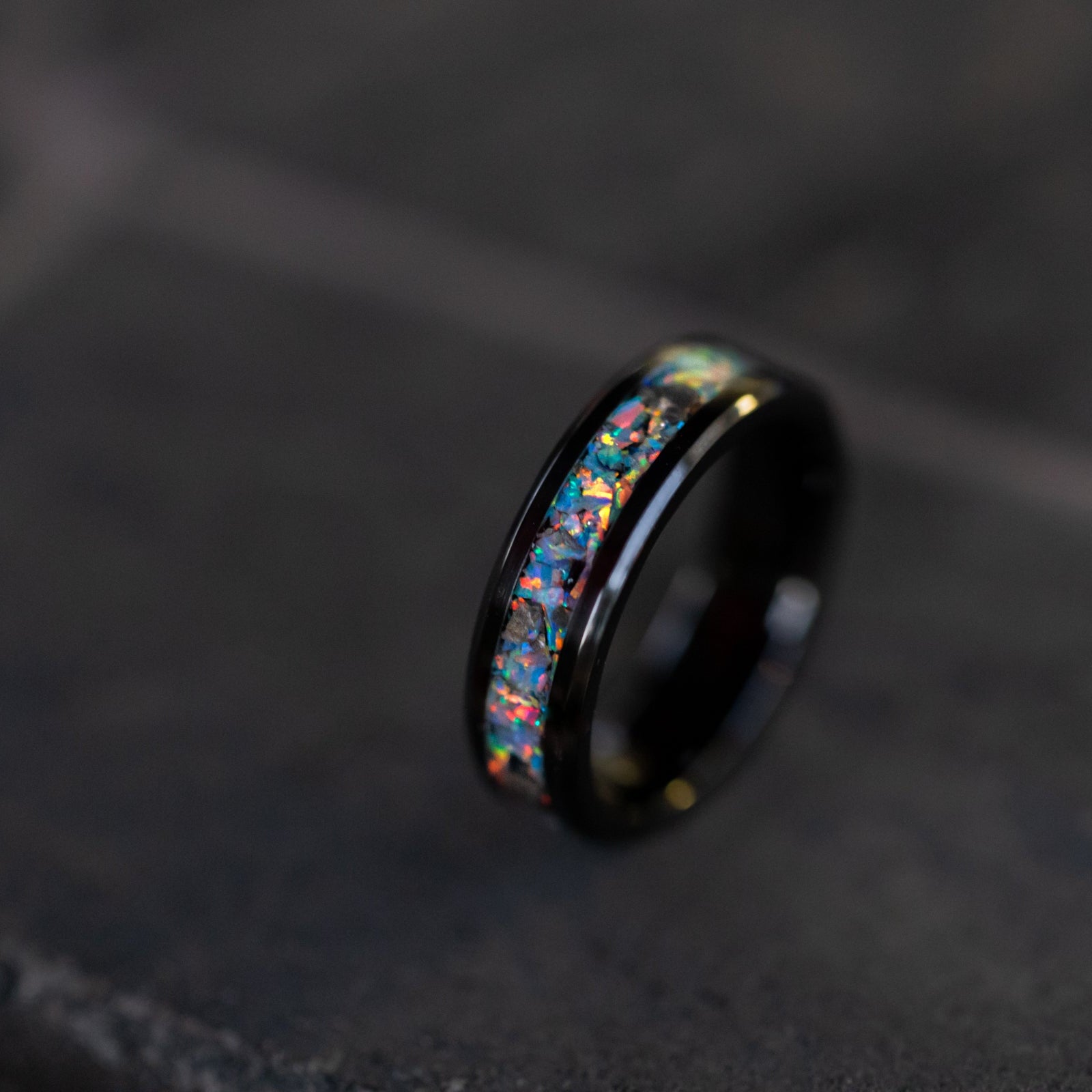 Close up of genuine lunar meteorite pieces surrounded by light gray rainbow moonstone opal inlay on beveled ceramic ring