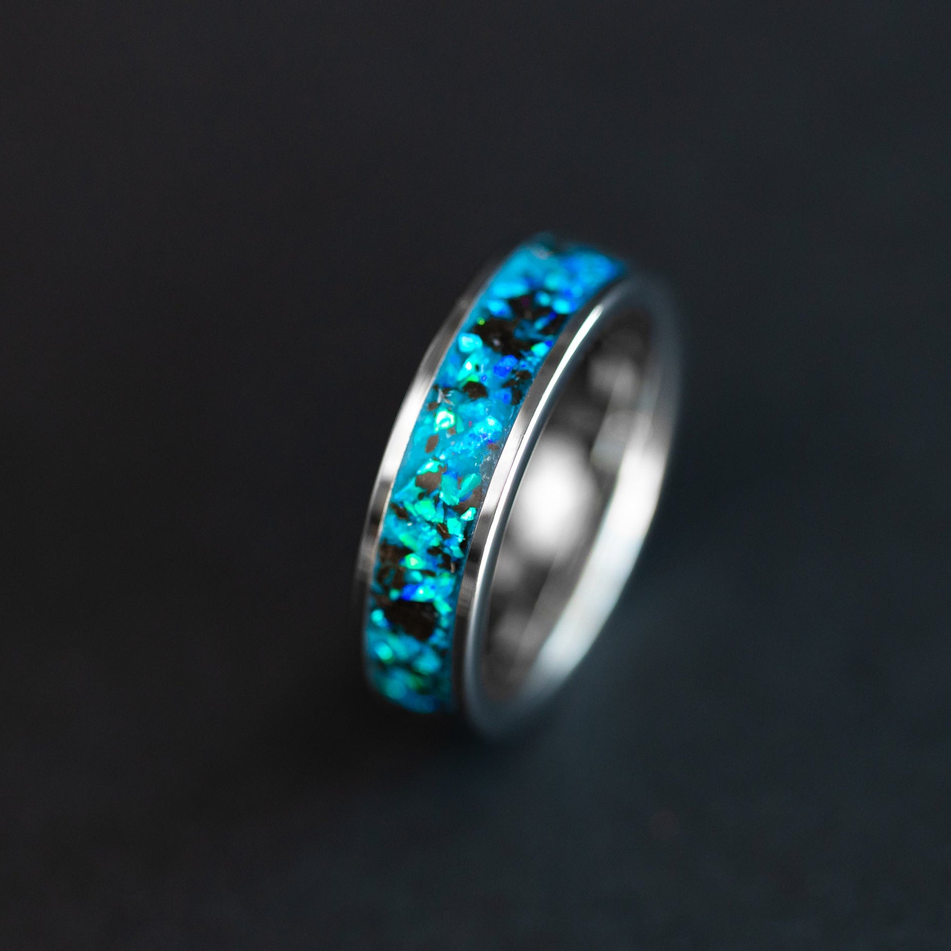 Megalodon Abyss ring glowing blue in the dark after UV light charge showing Megalodon tooth fossil suspended in luminous blue opal inlay