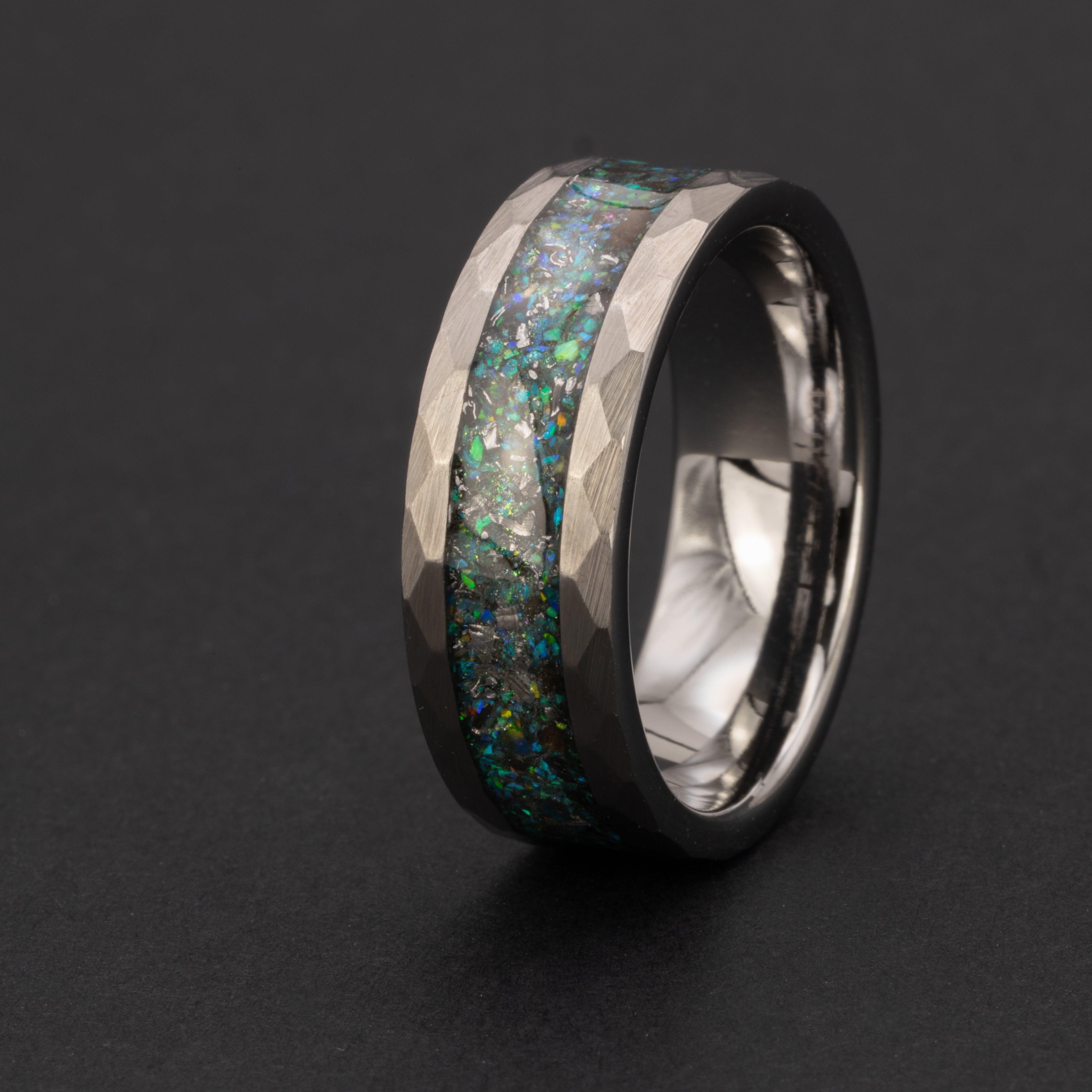 Close up of genuine Megalodon shark tooth and Campo del Cielo meteorite shavings suspended in blue and green opal glitter inlay on hammered tungsten ring