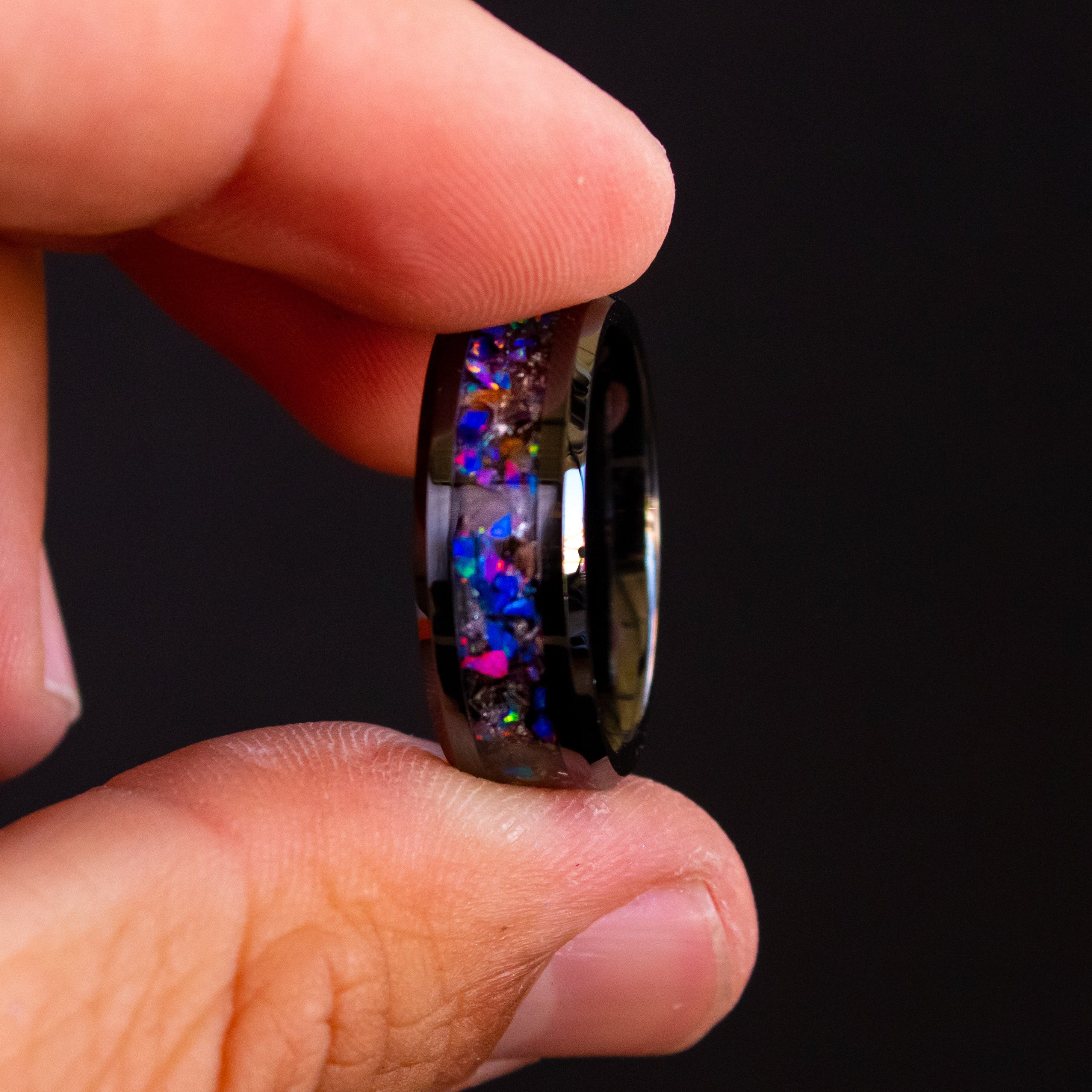 Detail shot of the Midnight Rex ring showing authentic T-Rex bone fragments and meteorite shavings catching light through midnight blue purple opal inlay on black ceramic band