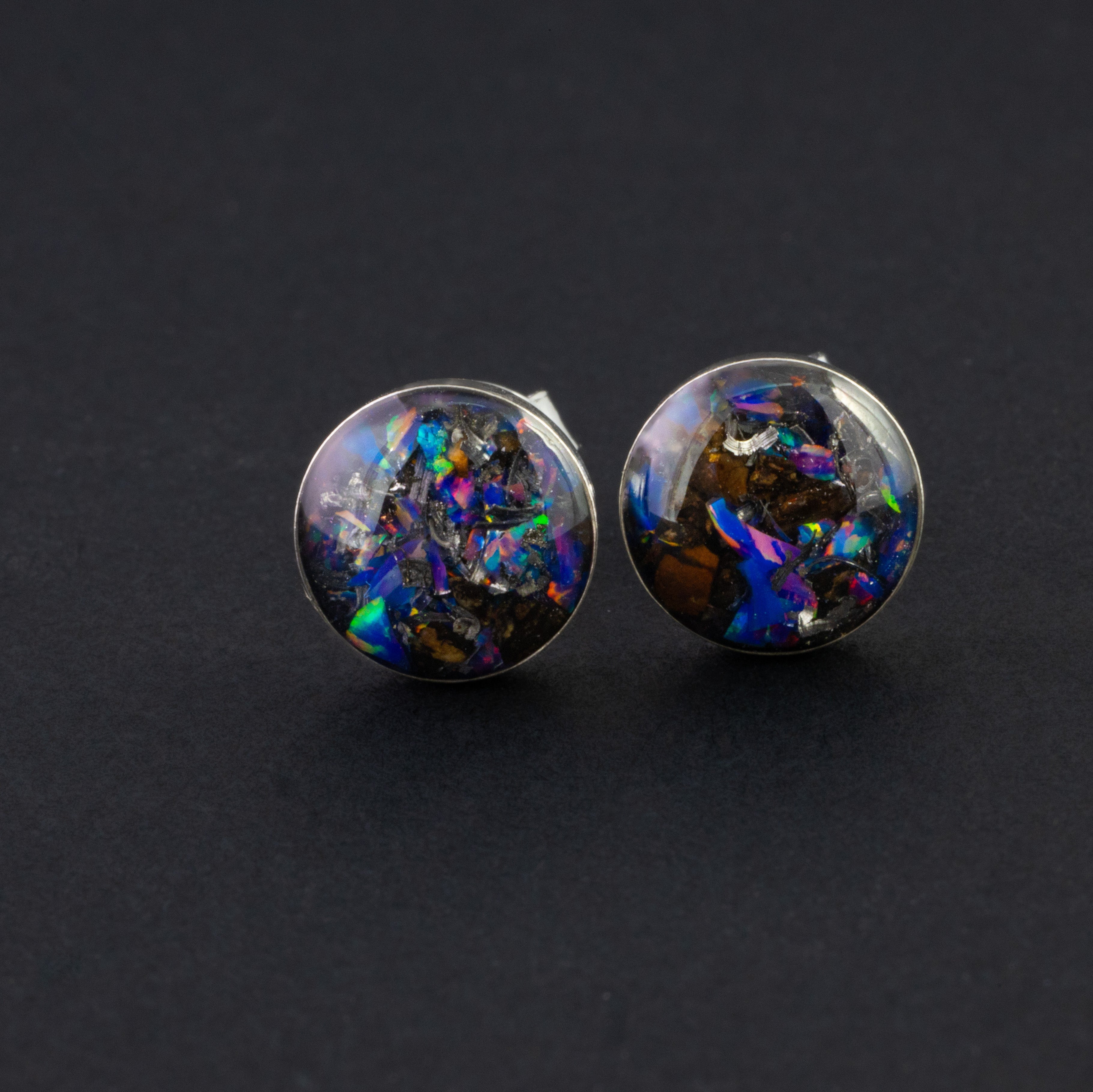 Close-up of the Midnight TRex Studs showing Campo Del Cielo iron meteorite, real T-Rex bone, and proprietary purple blue Midnight Opal in each stud
