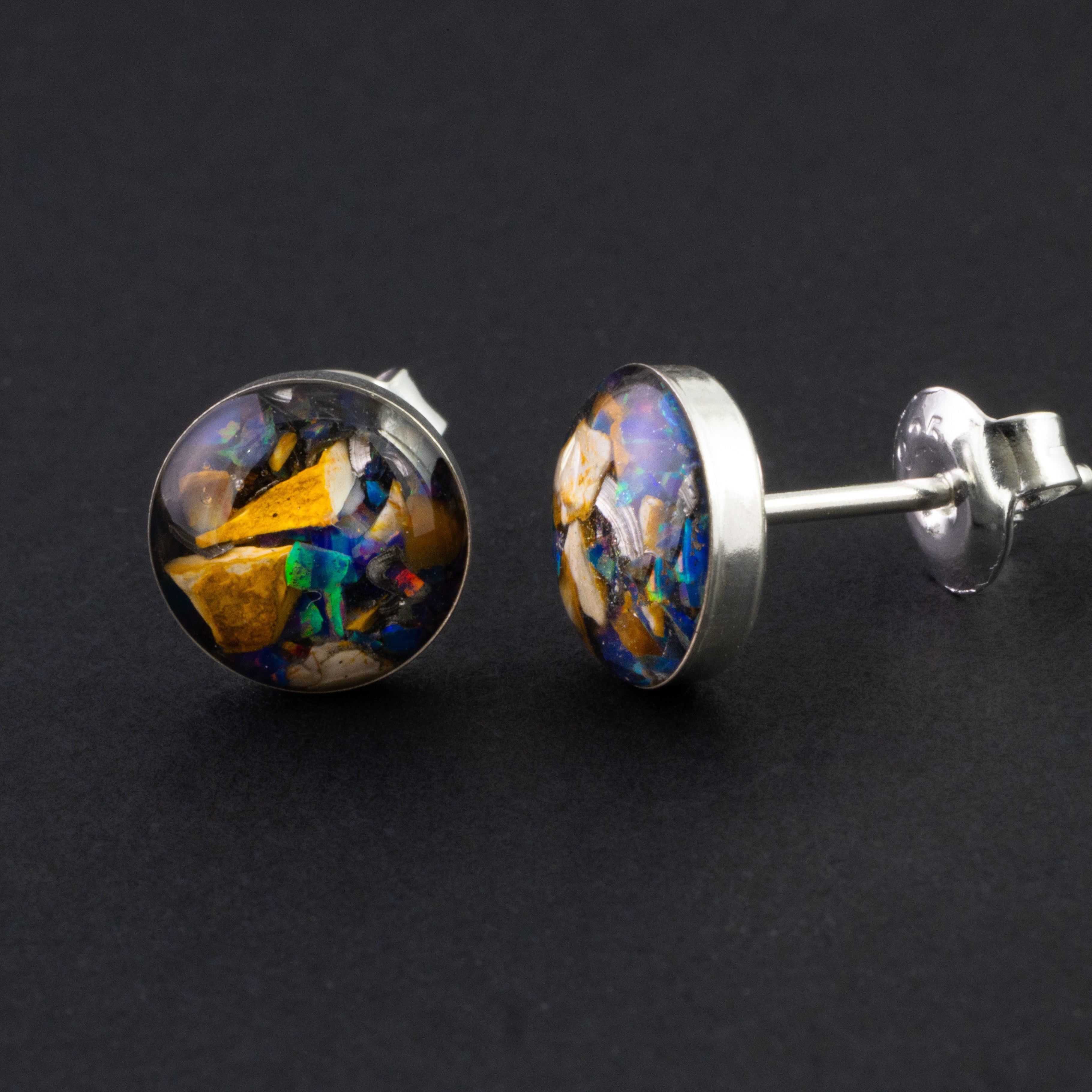 Close-up of the Midnight Velociraptor Stud showing Campo Del Cielo iron meteorite, real velociraptor bone, and proprietary purple blue Midnight Opal in each stud