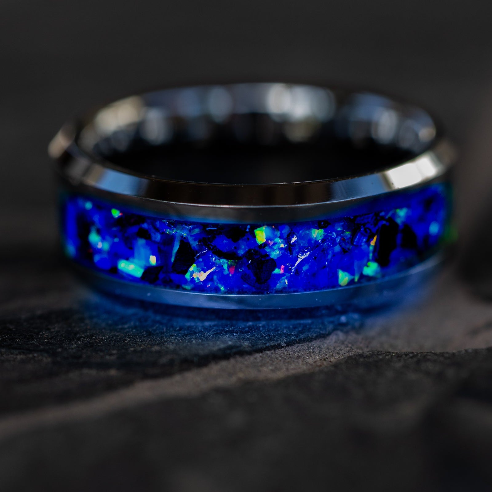 Oasis Rex Glow ring glowing blue in total darkness showing T-Rex bone and meteorite suspended in electric blue glow in the dark inlay