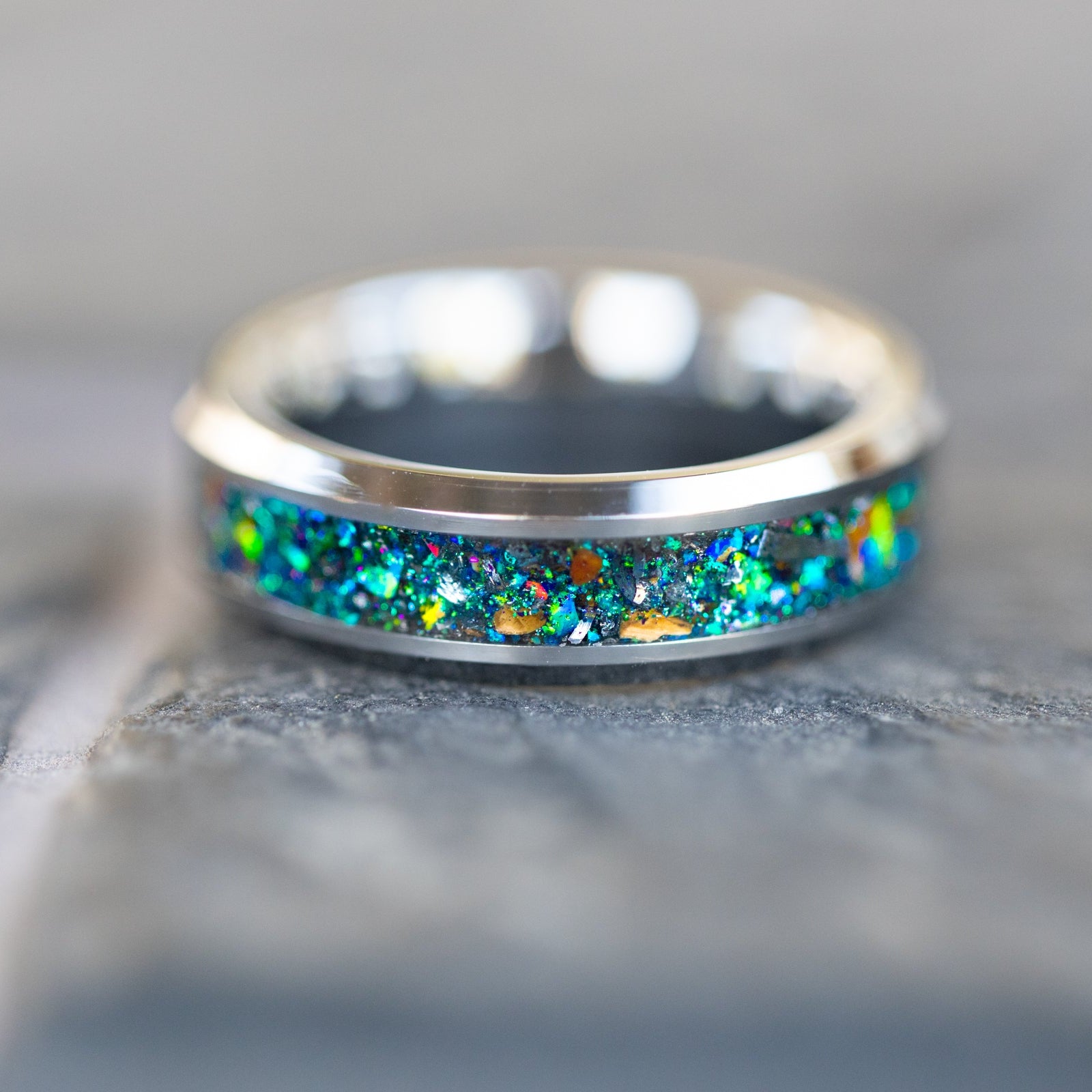 Detail shot of the Prismatic Raptor ring showing authentic Velociraptor bone fragments and meteorite shavings catching light through multi-color opal galaxy inlay