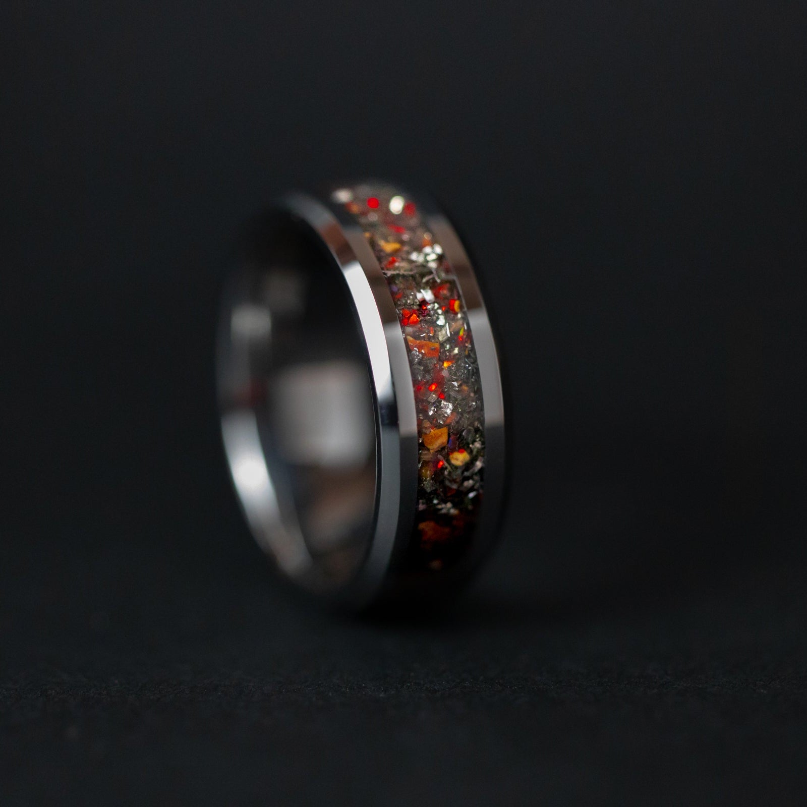 Detail shot of the Raptor Flare ring showing authentic Velociraptor bone fragments and meteorite shavings with flashes of red opal catching light