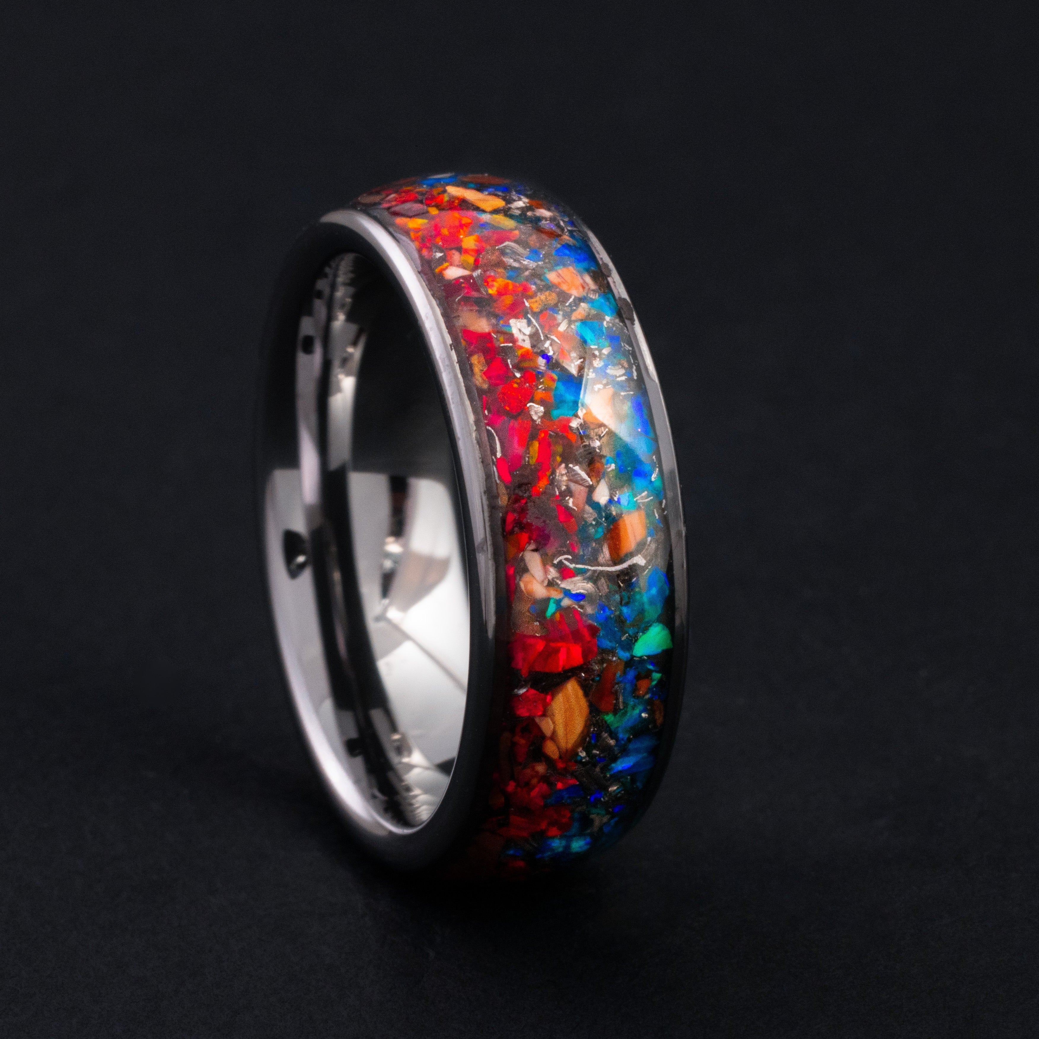 Close up of genuine Velociraptor fossil shards and fire and ice opals in a silver tungsten ring.