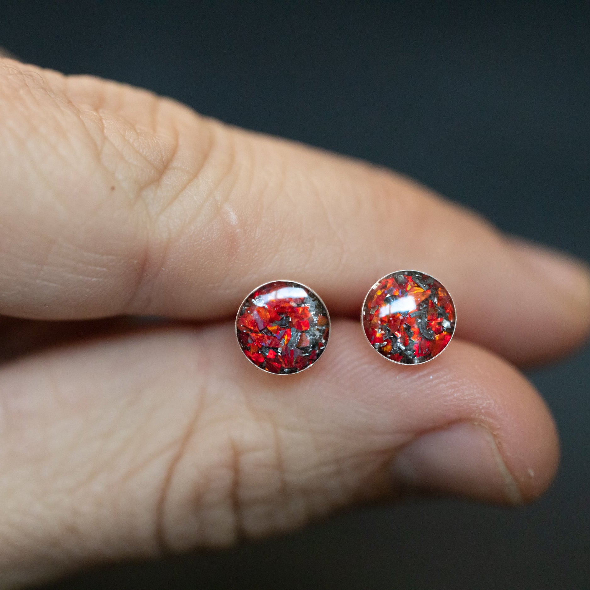 Close-up of the Red Opal Studs ruby red stud earrings showing Campo Del Cielo iron meteorite set with vivid red opal evoking the look of fire opal