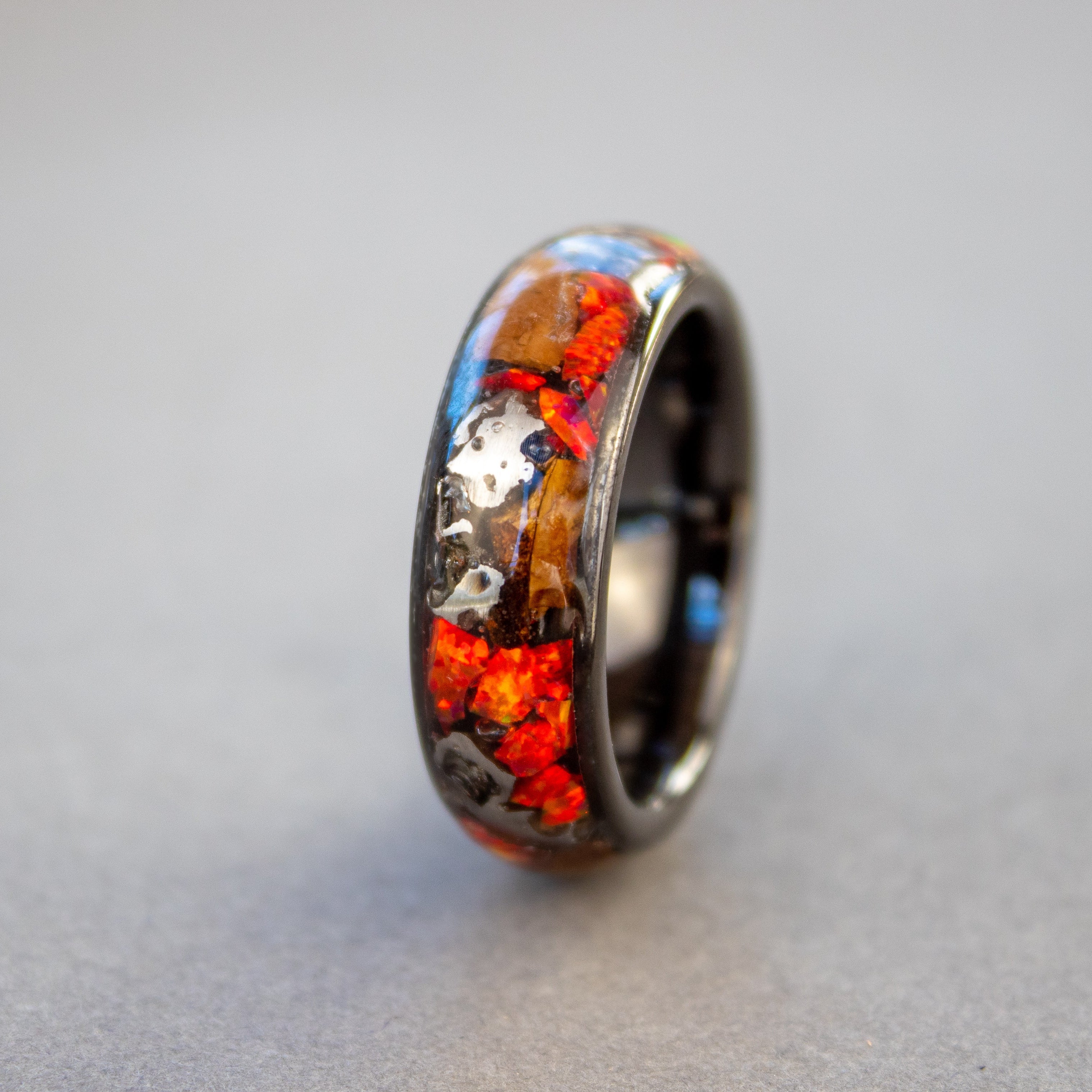 Handcrafted 8mm wide channel black ceramic mens wedding band with large authentic Triceratops bone and Campo del Cielo meteorite pieces in red opal inlay made in California