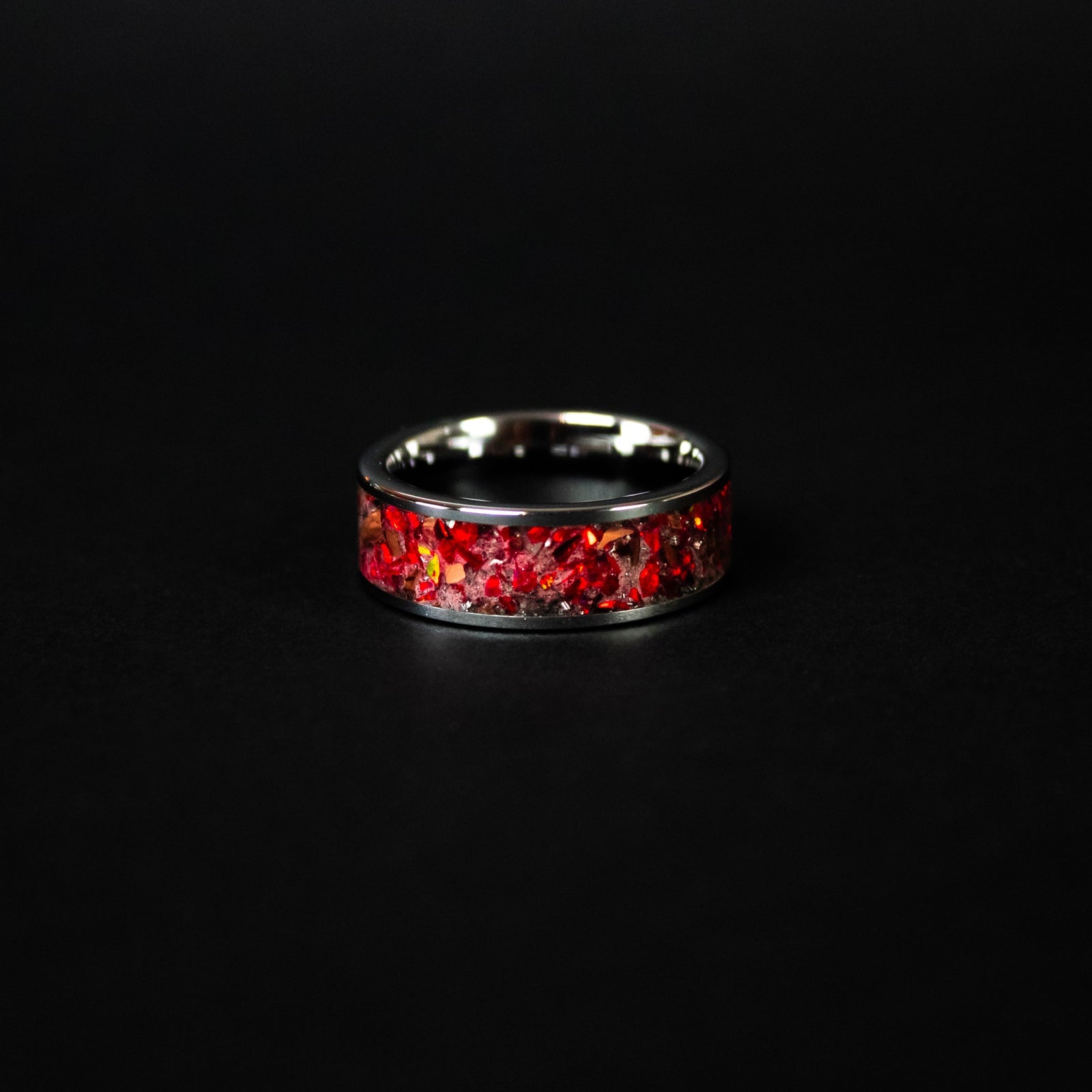 Red Rex Glow ring glowing red in total darkness showing T-Rex bone and meteorite suspended in electric red glow in the dark inlay