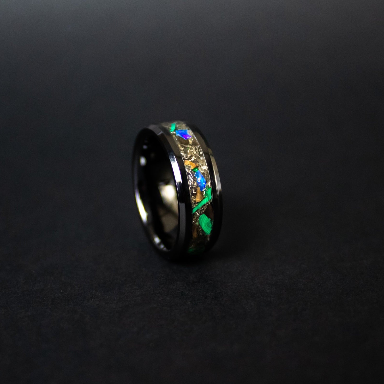 Detail shot of the Rex Terra ring showing authentic T-Rex bone, meteorite shavings, green malachite bands, and Ethiopian Opal fire play on black ceramic band