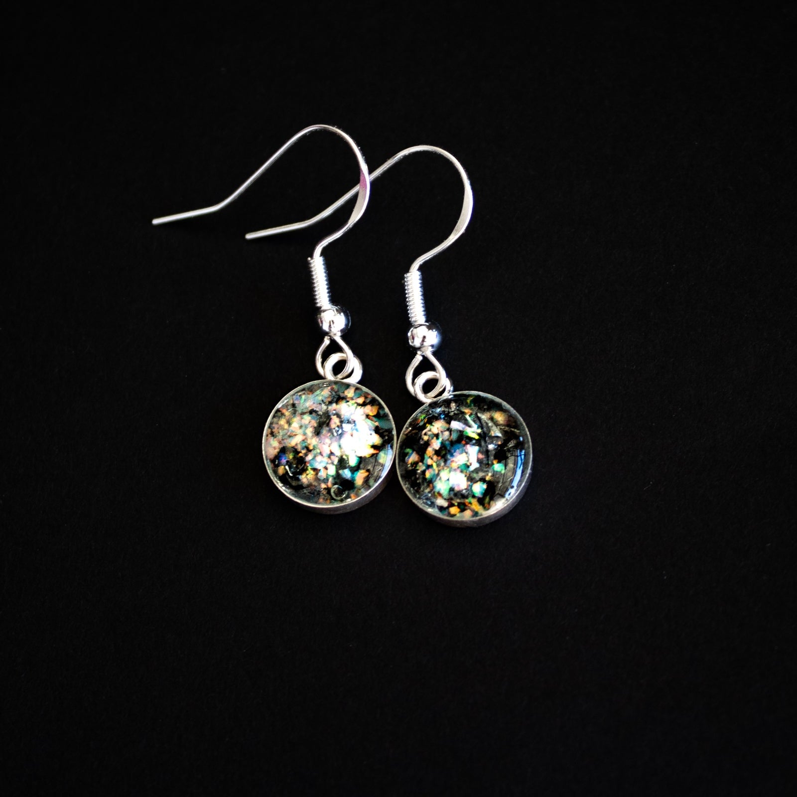Close-up of the Shimmer Meteorite Dangle drop earrings showing Campo Del Cielo iron meteorite set with iridescent white opal flashing pink, blue, and green