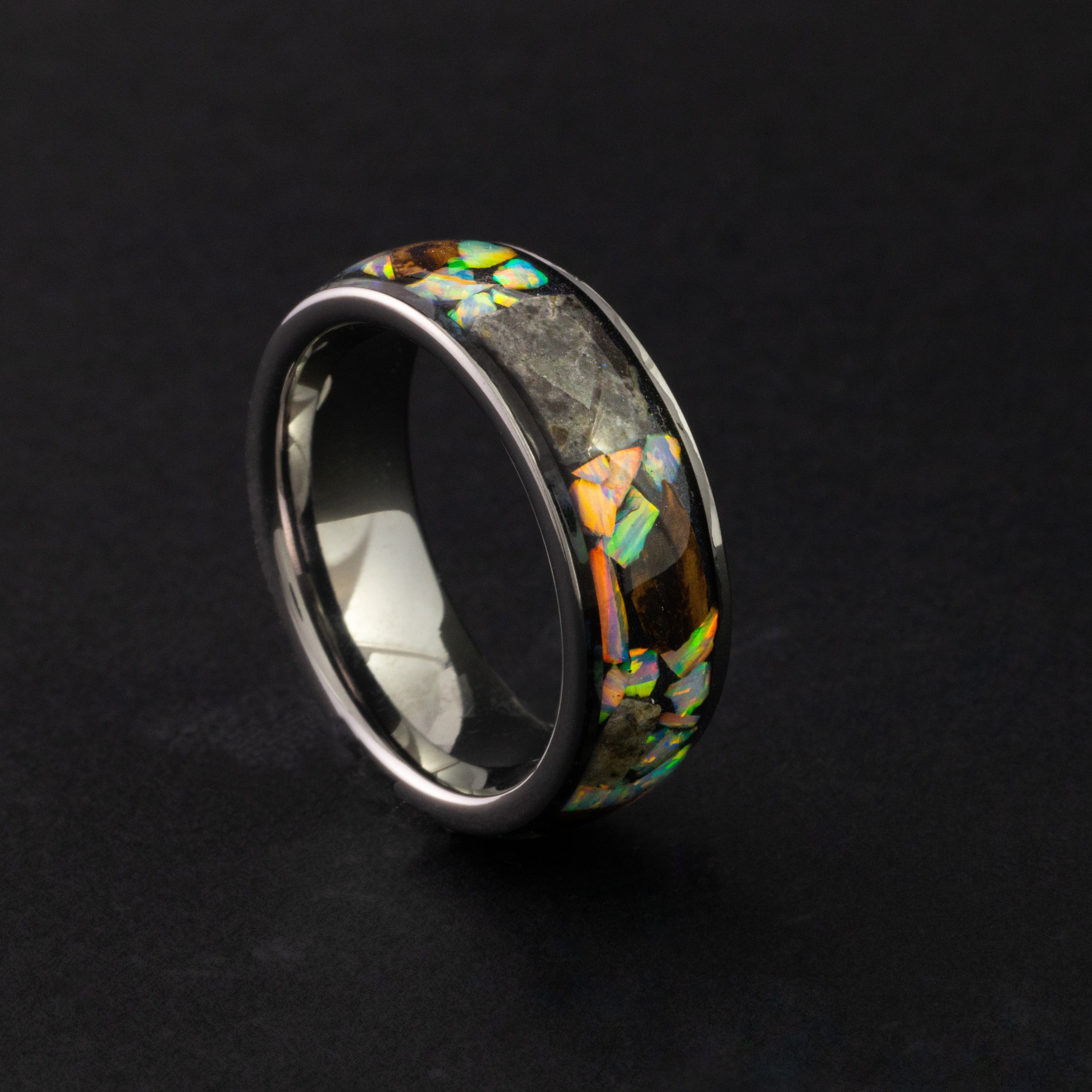 Close up of large genuine T-Rex fossil pieces and lunar meteorite chunks surrounded by white pearl opal inlay on wide channel tungsten ring