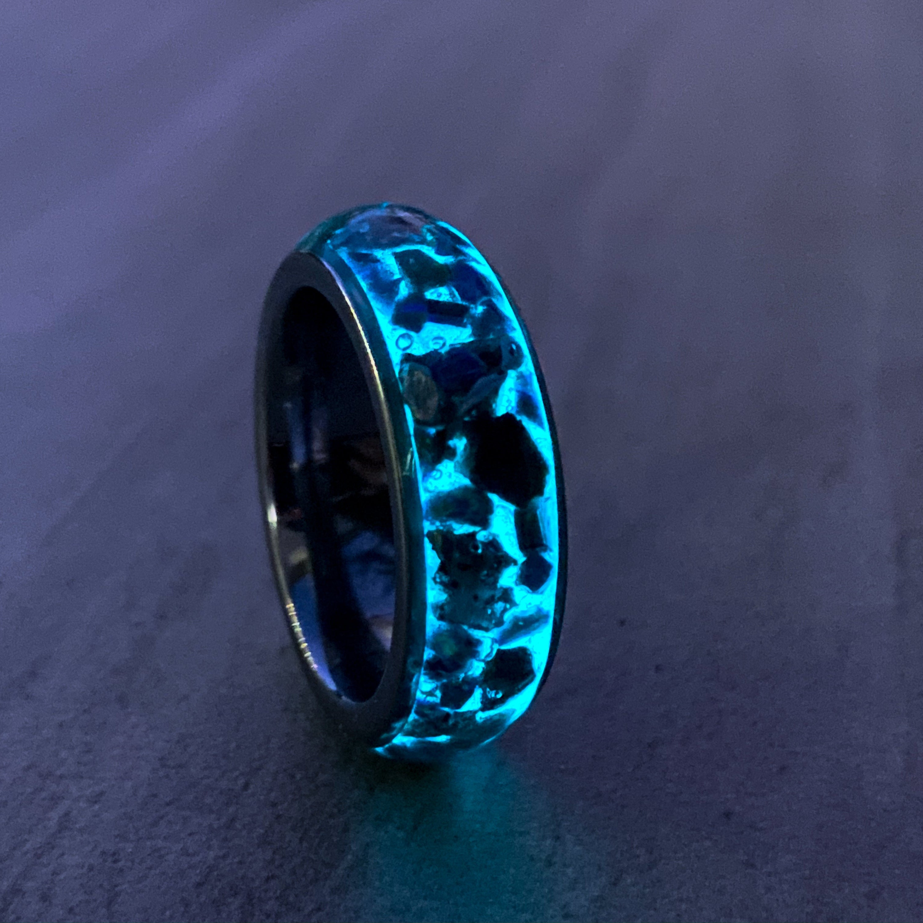 Close up of large genuine T-Rex fossil pieces and Campo del Cielo meteorite chunks surrounded by blue and green opal inlay on wide channel tungsten ring