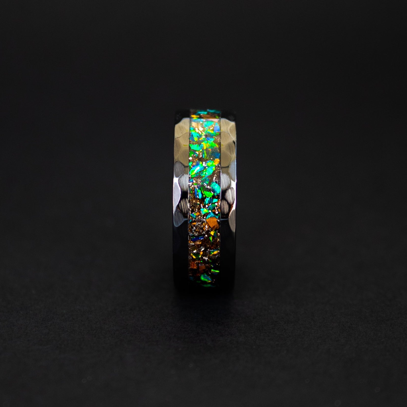 Close up of genuine T-Rex fossil and Campo del Cielo meteorite shavings suspended in green opal inlay on hammered black ceramic ring